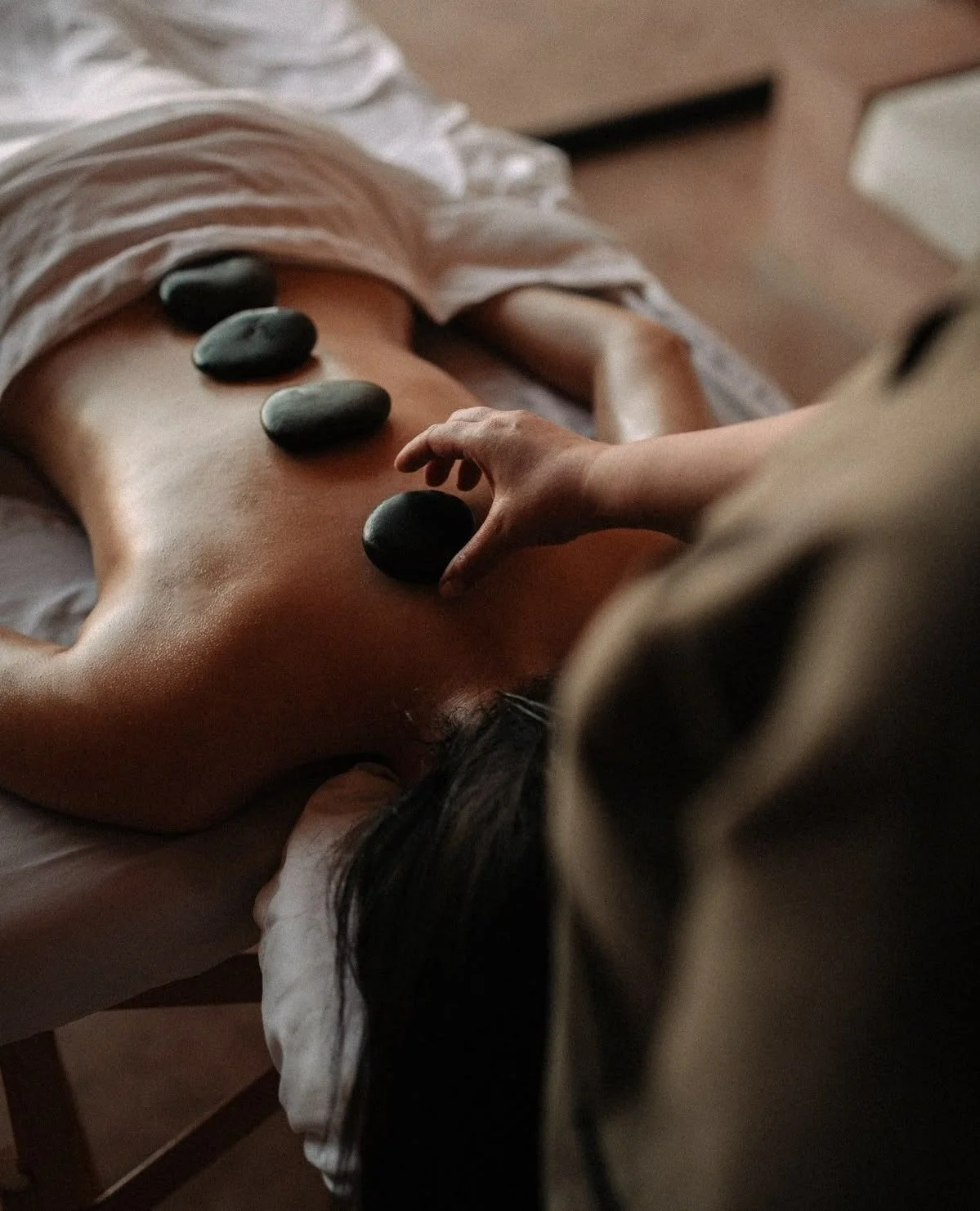A person receiving a hot stone massage on their back.
