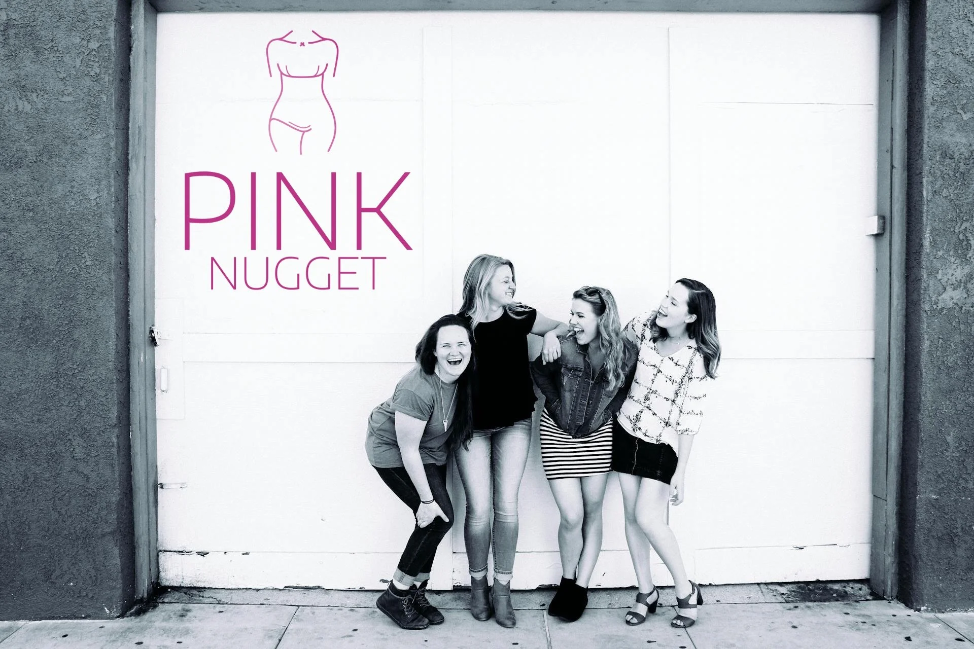 Vier lachende Frauen stehen vor einer weißen Wand mit Pink Nugget Logo, sie lachen und umarmen sich, die Szene ist in Schwarz-Weiß mit Pinkem Logo.