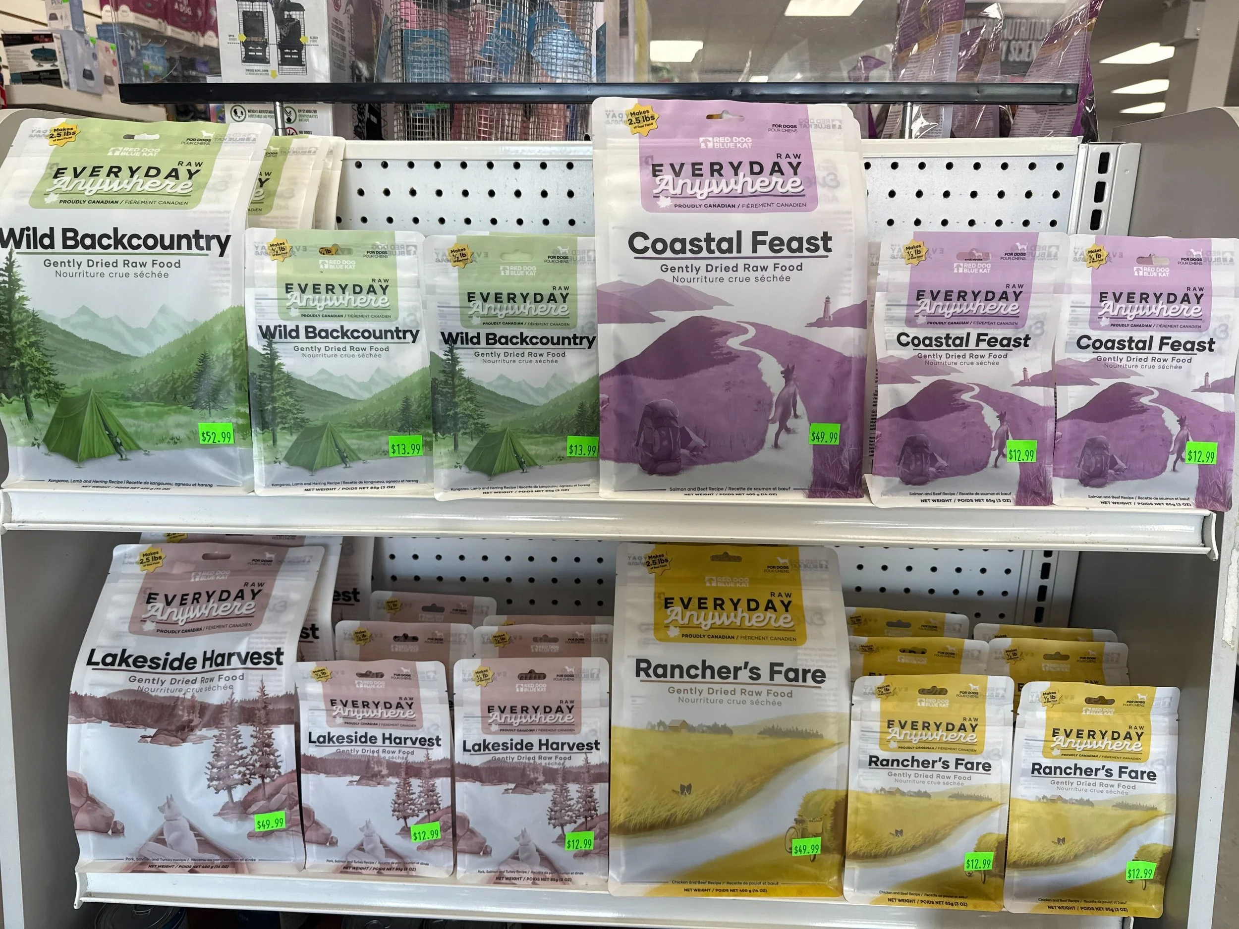 Shelves stocked with various bags of Gently Dried Raw Food for pets, including brands Wild Backcountry, Coastal Feast, Lakeside Harvest, Rancher's Fare, and others. The bags feature outdoor and nature-themed designs with prices ranging from about $12.99 to $52.99.