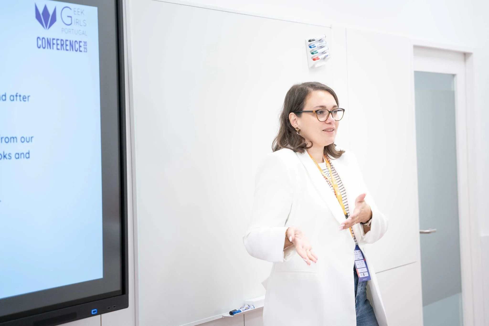 Olga Kuvshinova presenting at Geek Girls Portugal Conference 2023, standing beside a large screen with presentation slides.