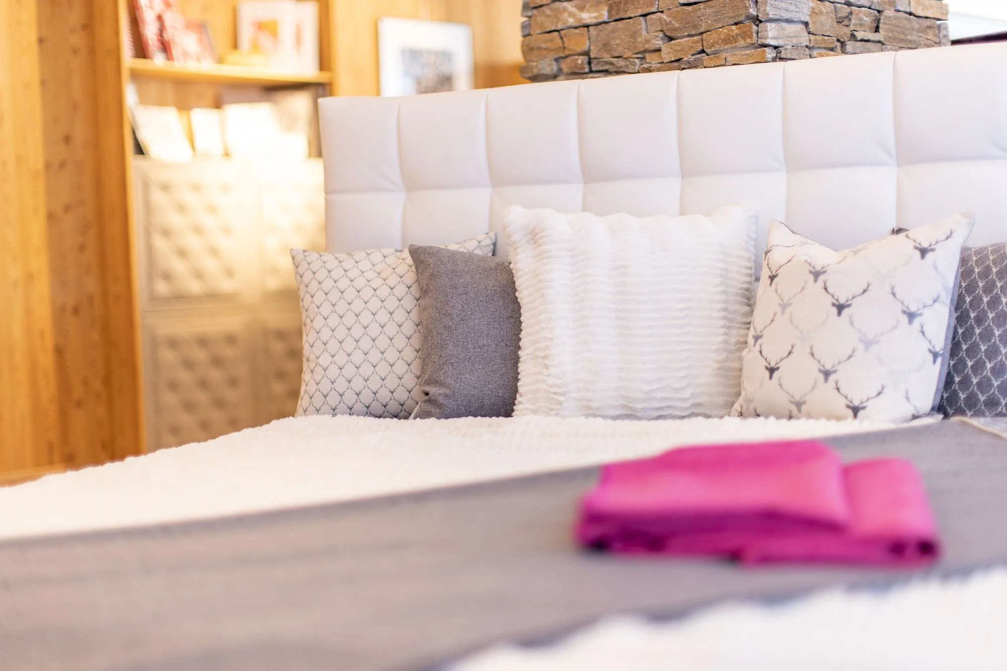Ein Bett mit weißen Kissen, Bettdecke und pinker Stoffdecke in einem Schlafzimmer mit Holzmöbeln.