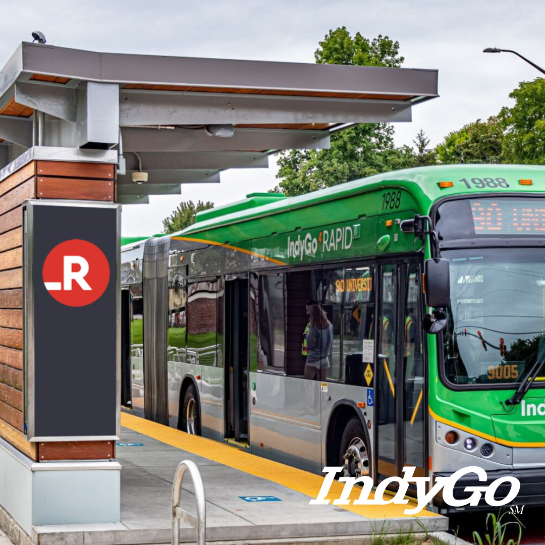 Green IndyGo Rapid bus pulling into a station on a cloudy day.