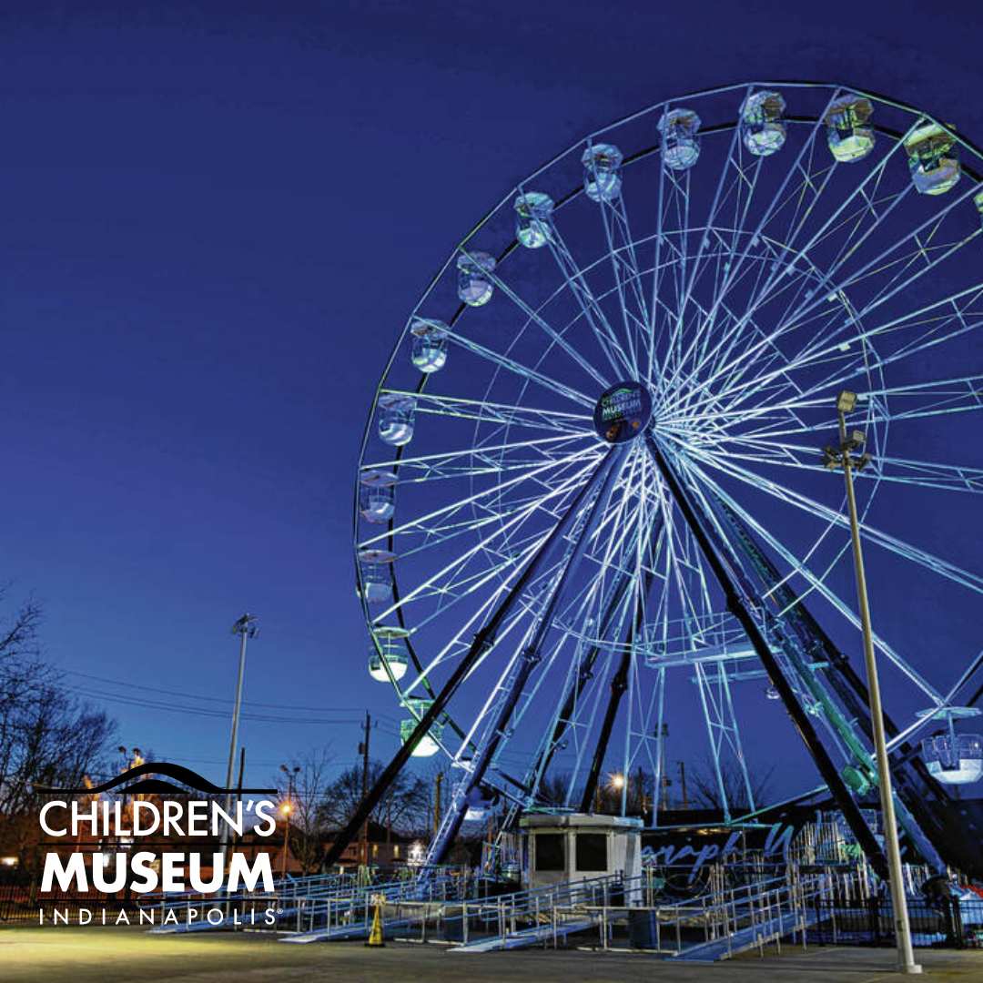 A large illuminated Ferris wheel at night at the Children's Museum in Indianapolis.