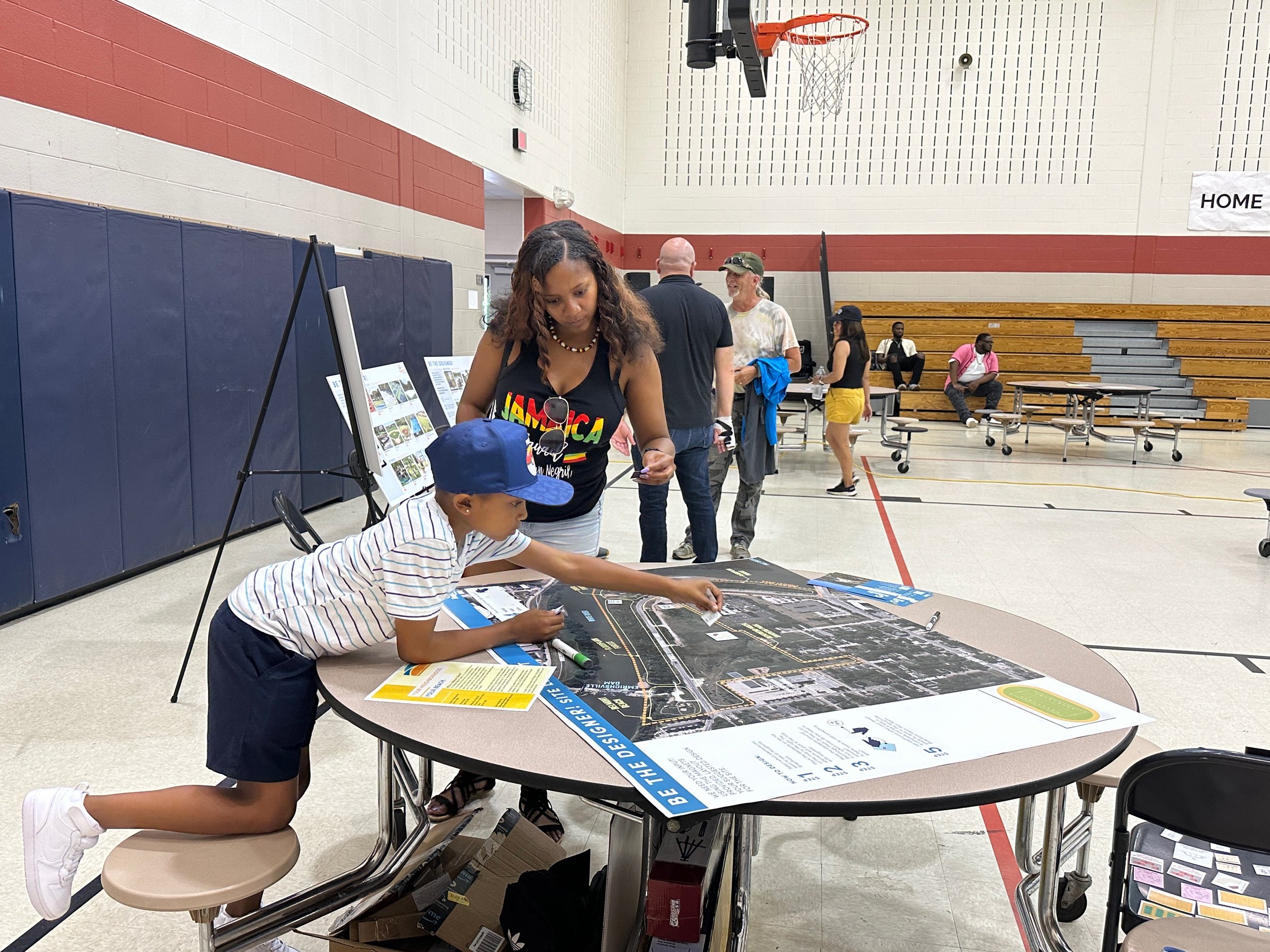 Person hanging a printed document on a gray wall with hands, manicured nails, and a ring, in an indoor office setting.