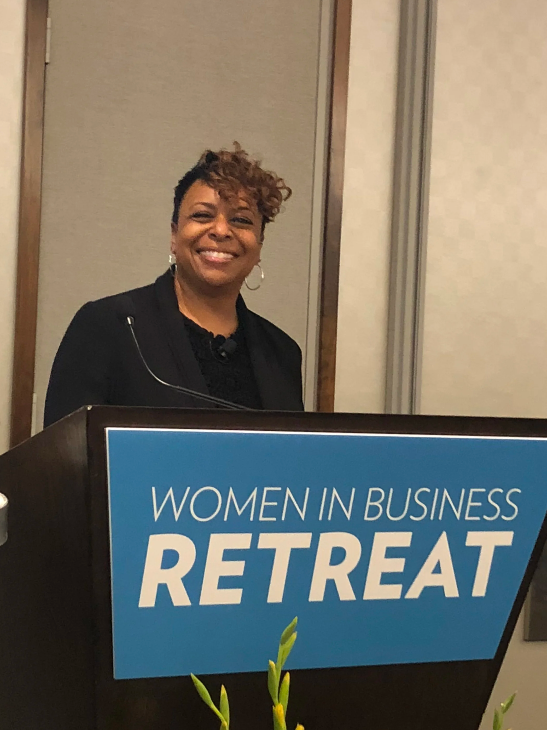 Group of diverse young people and adults standing in a classroom or conference room, smiling for a photo.