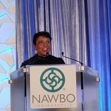 Group of diverse young people and adults standing in a classroom or conference room, smiling for a photo.