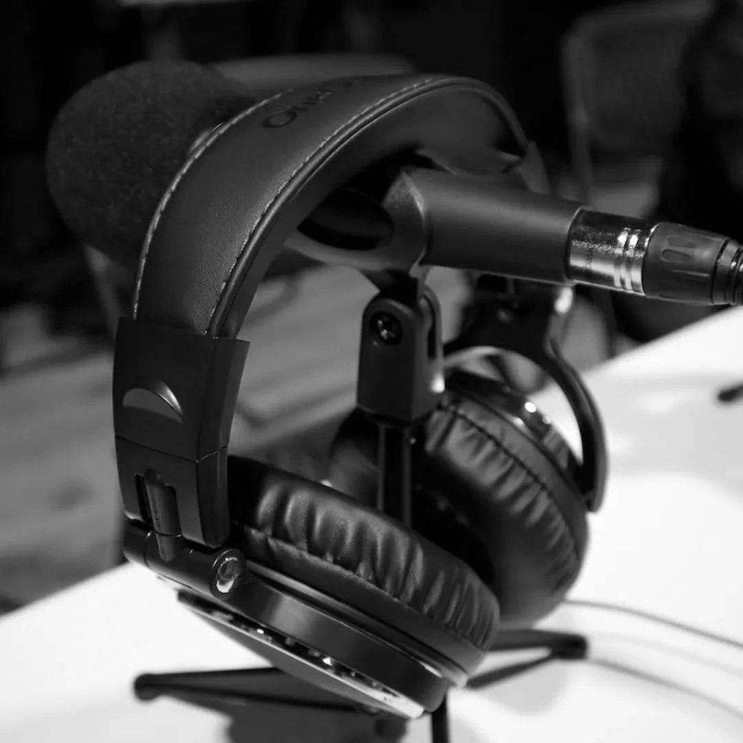Black over-ear headphones resting on a table with a microphone in the background.