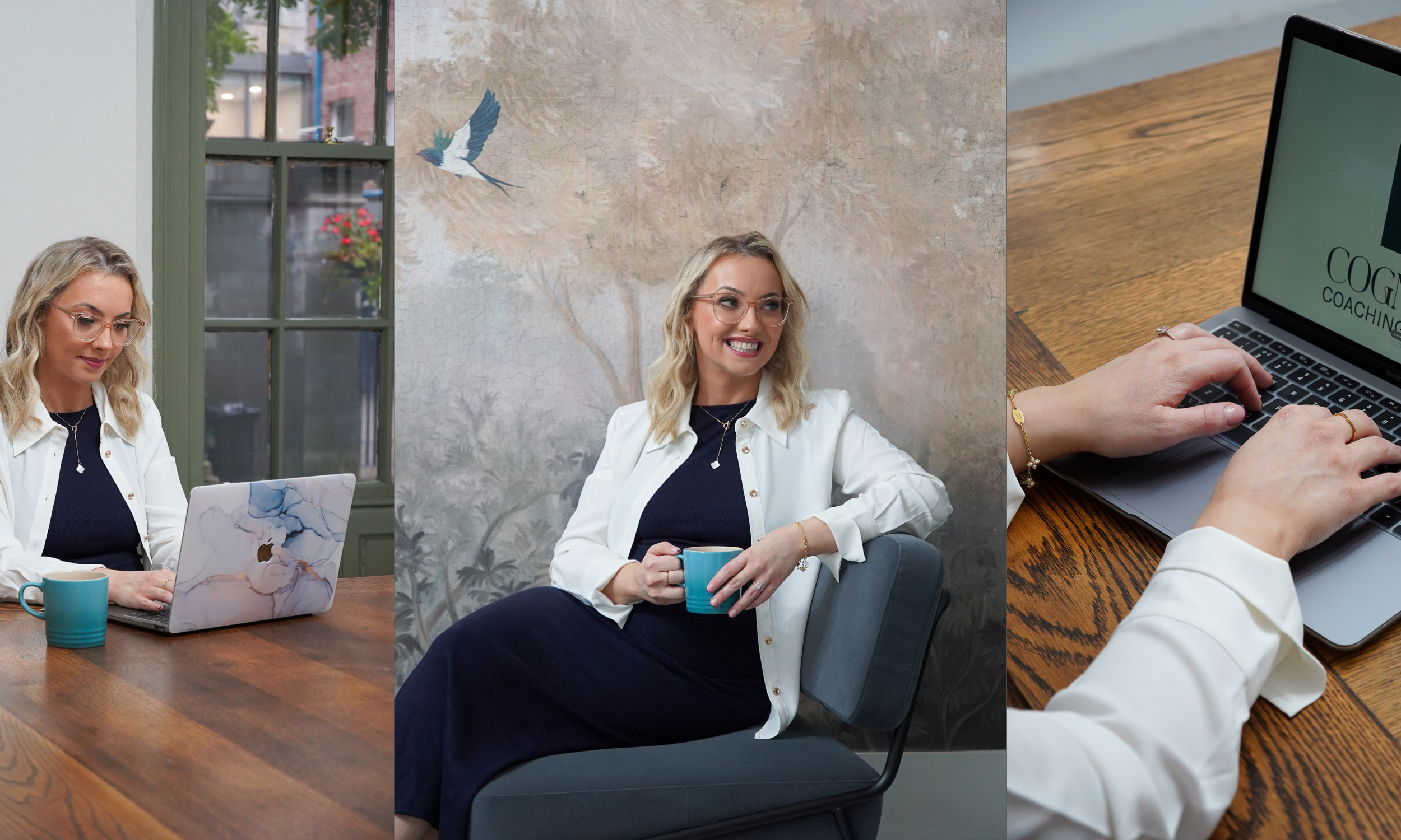 A woman sitting at a wooden table with a laptop, a mug, and a window in the background, in a cozy indoor setting.
