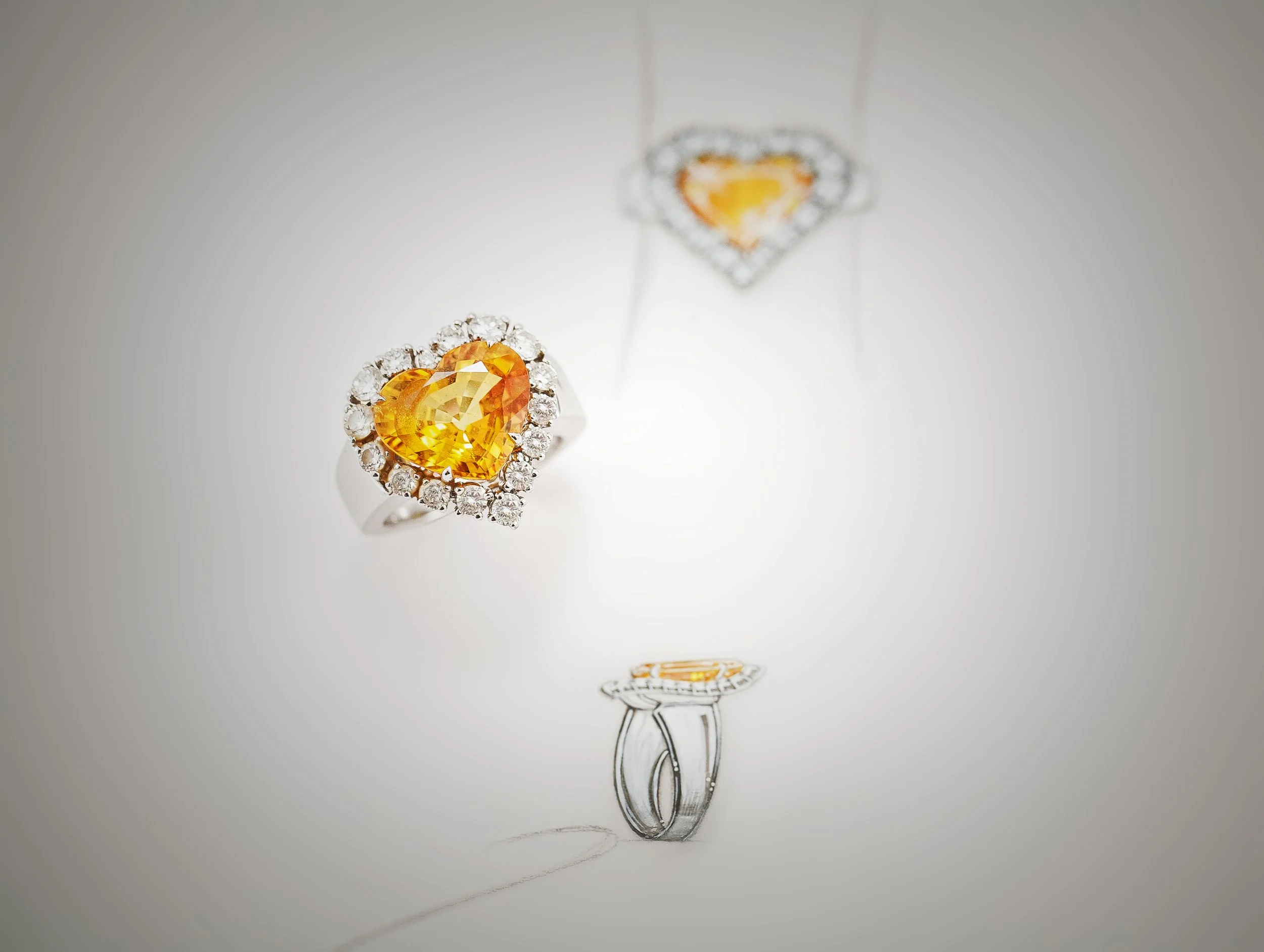 A pair of rings, each with a large, orange, heart-shaped gemstone surrounded by small clear stones, displayed on a drawing of a fork and a table setting.
