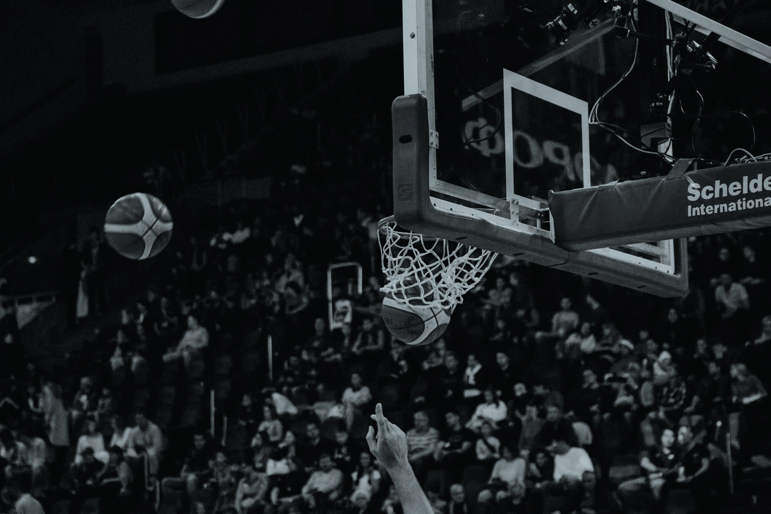 Basketball going through hoop with crowd watching in background