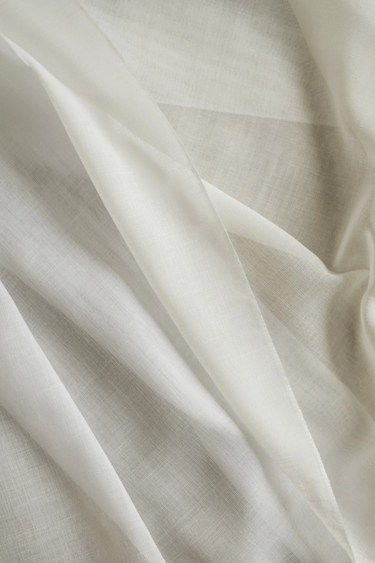 Close-up of cream-colored fabric with a subtle grid pattern and soft folds.