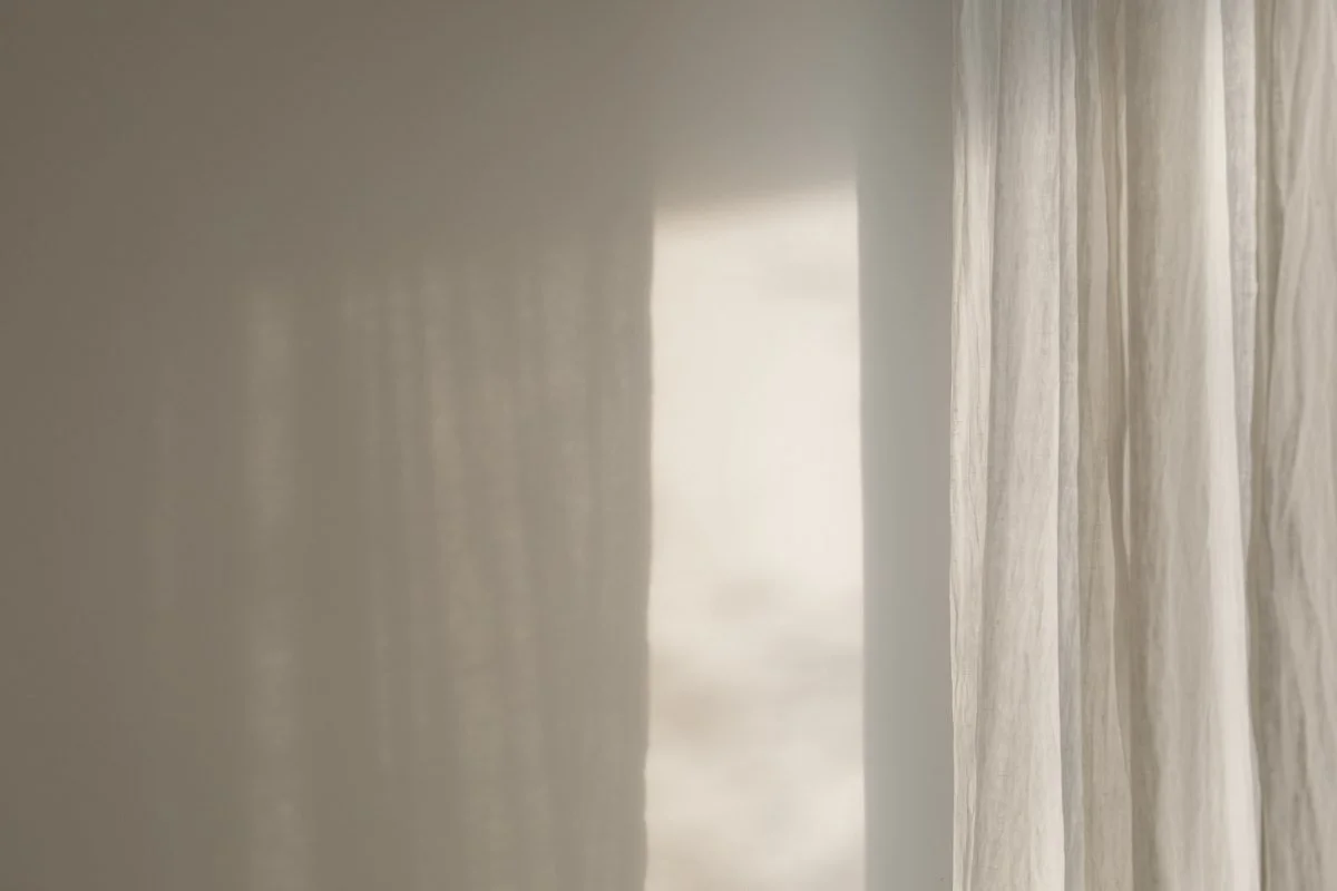 Close-up of sheer curtains with sunlight filtering through.