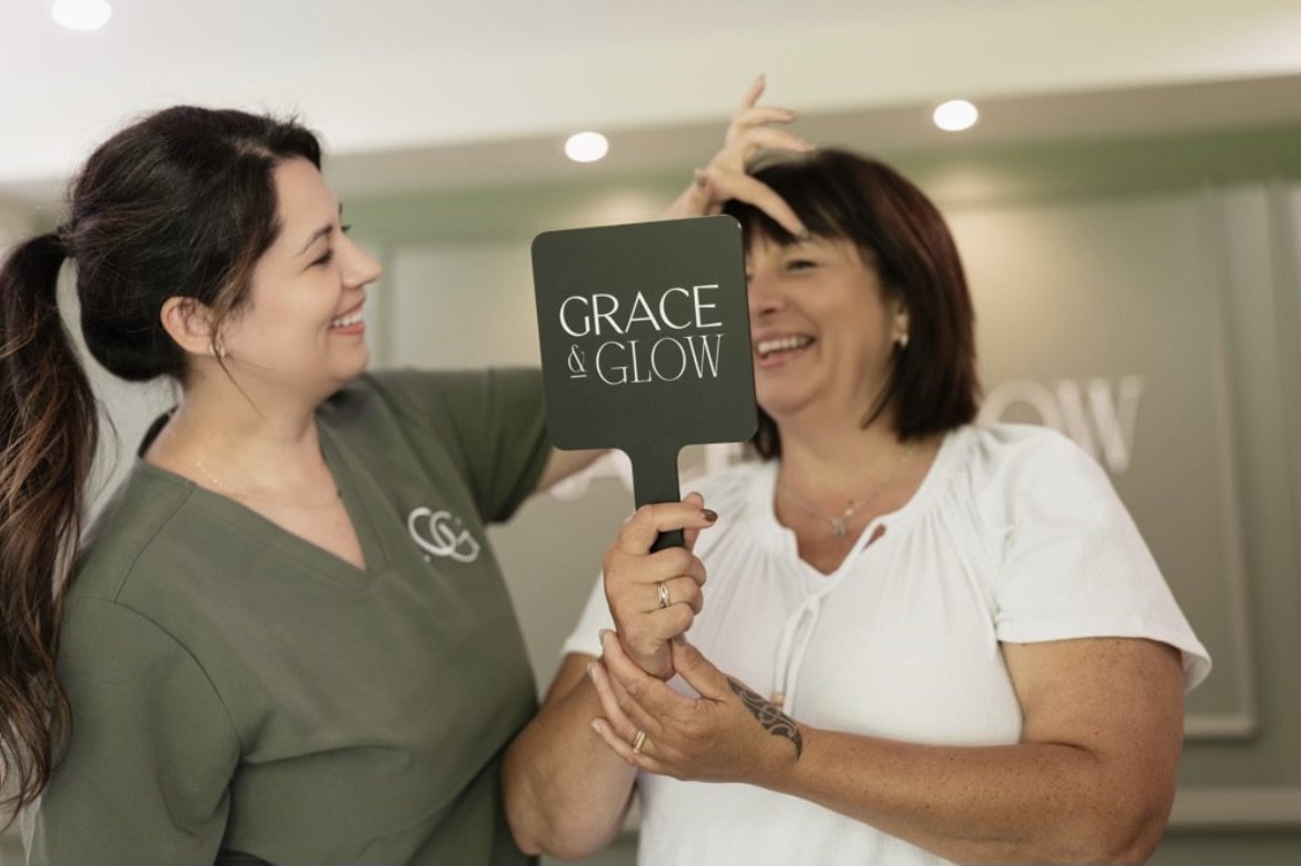 Lady wearing free uniform standing next to lady in white t-shirt holding black handheld mirror