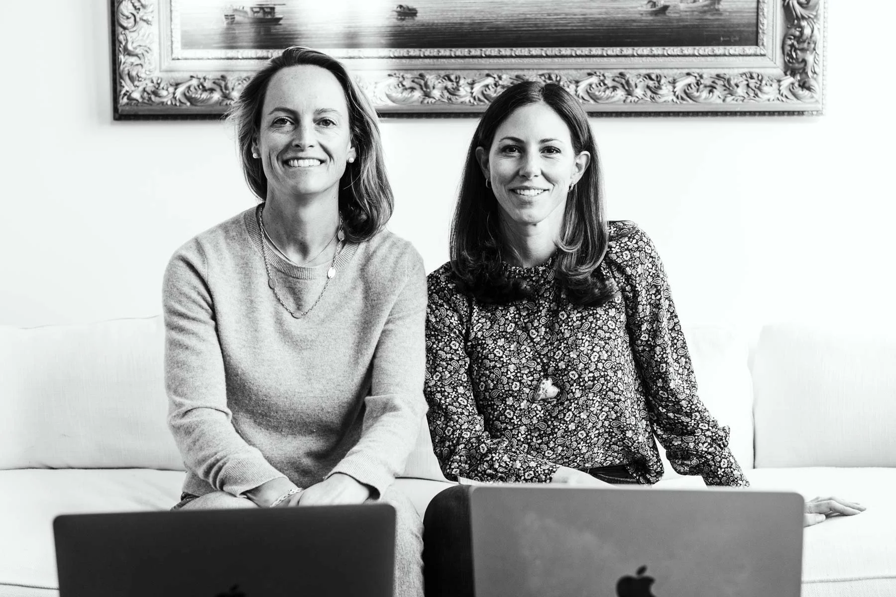 Registered dietitian and health coach founders of Noos sitting with laptops discussing nutrition and health coaching.