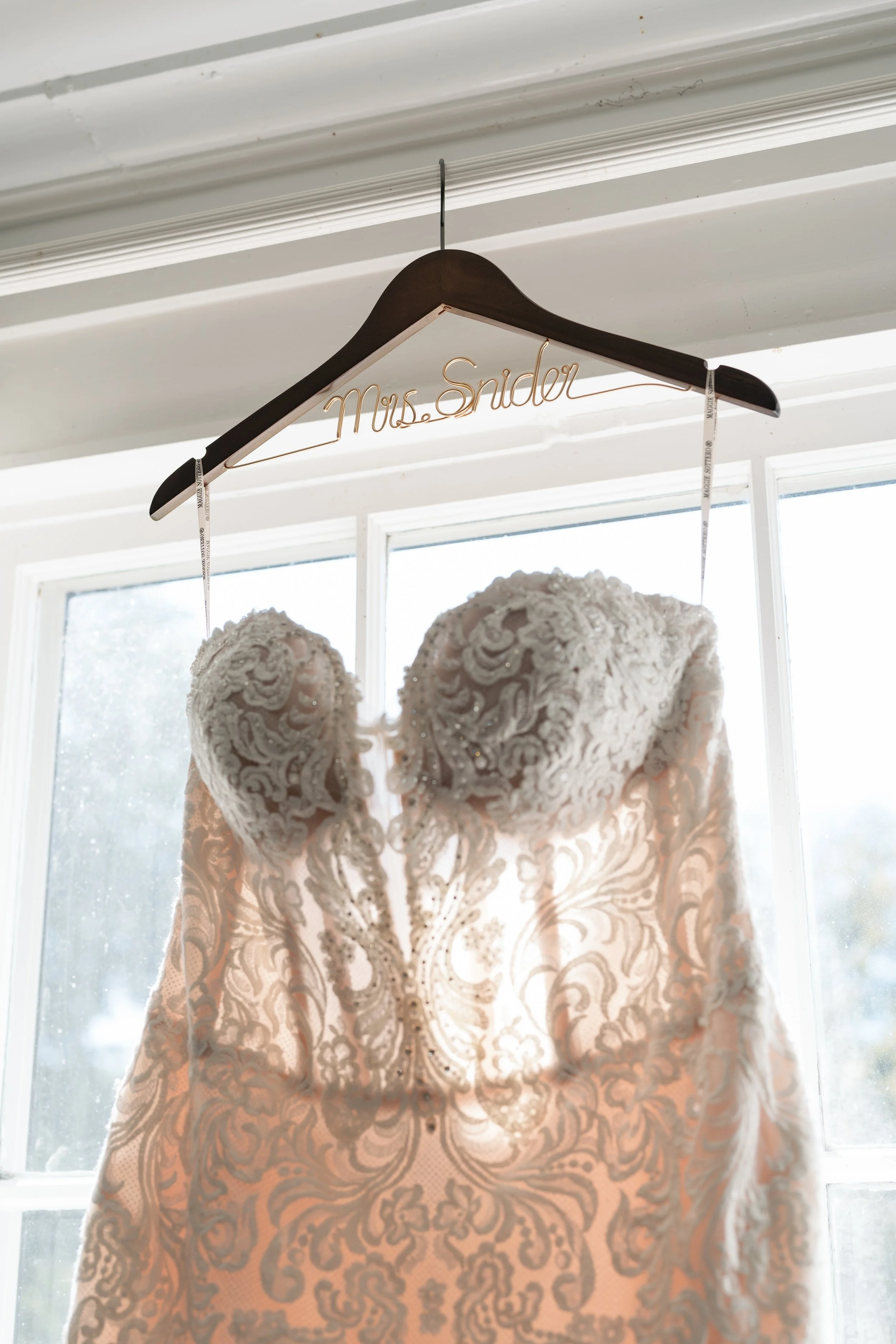 Lace wedding gown on custom engraved hanger in window light, Tennessee wedding photographer