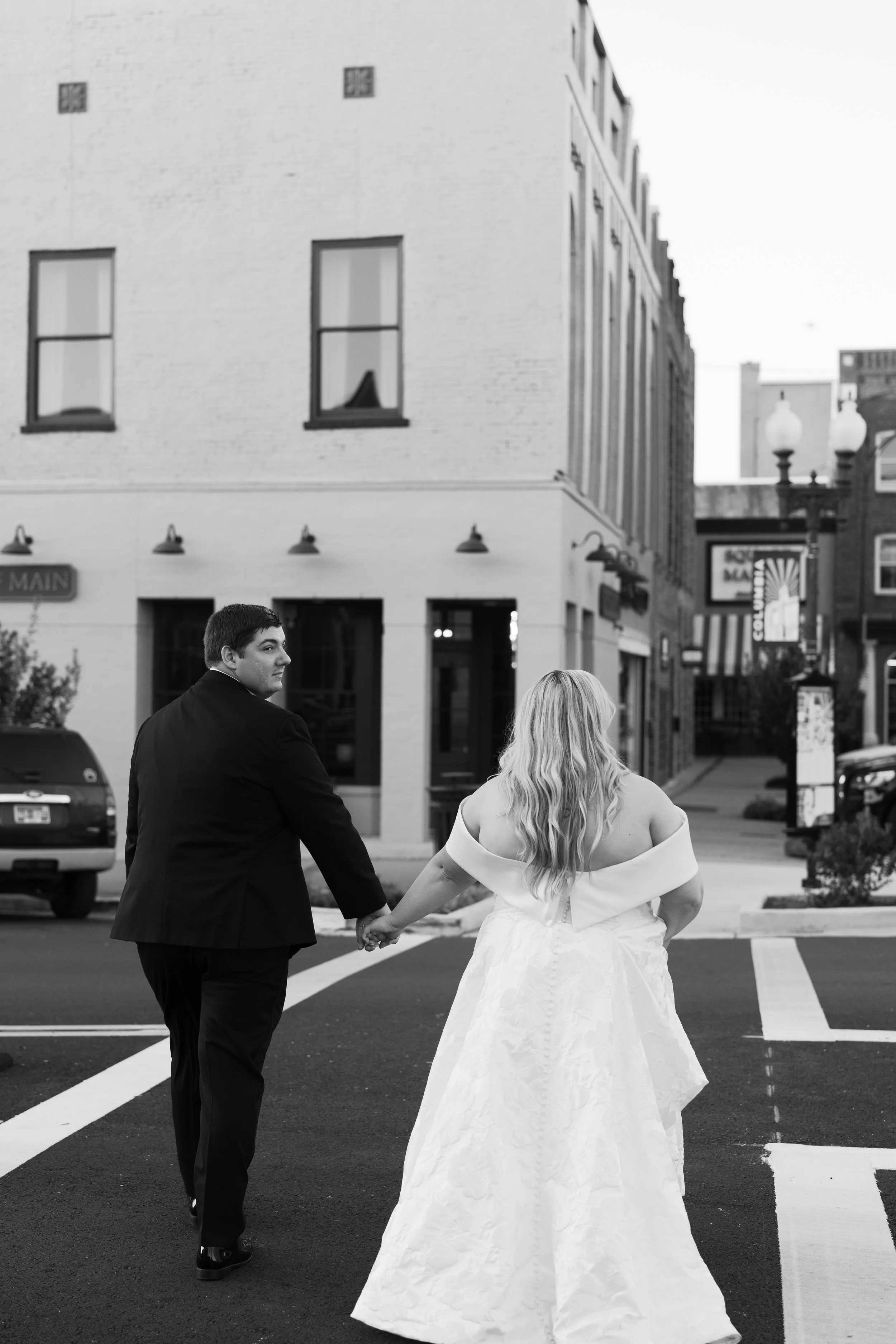 Bride and groom walking hand in hand down downtown street, West Tennessee wedding photographer
