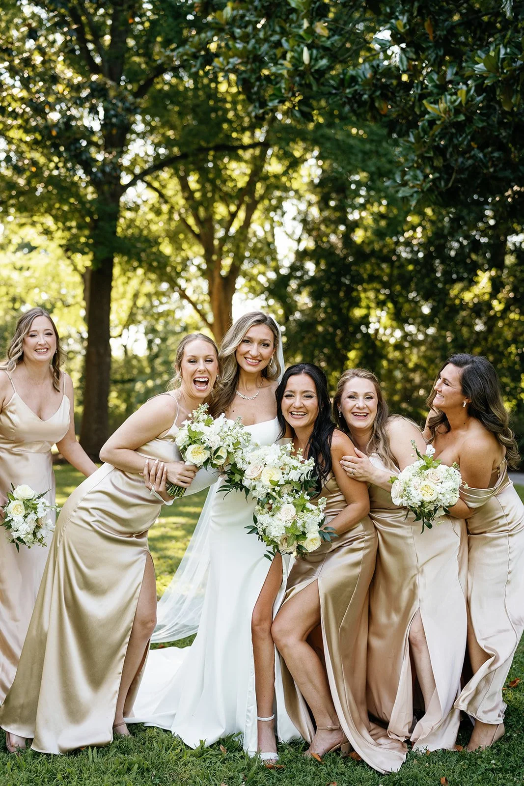 Bride and bridesmaids laughing together outdoors in champagne dresses, Tennessee wedding photographer