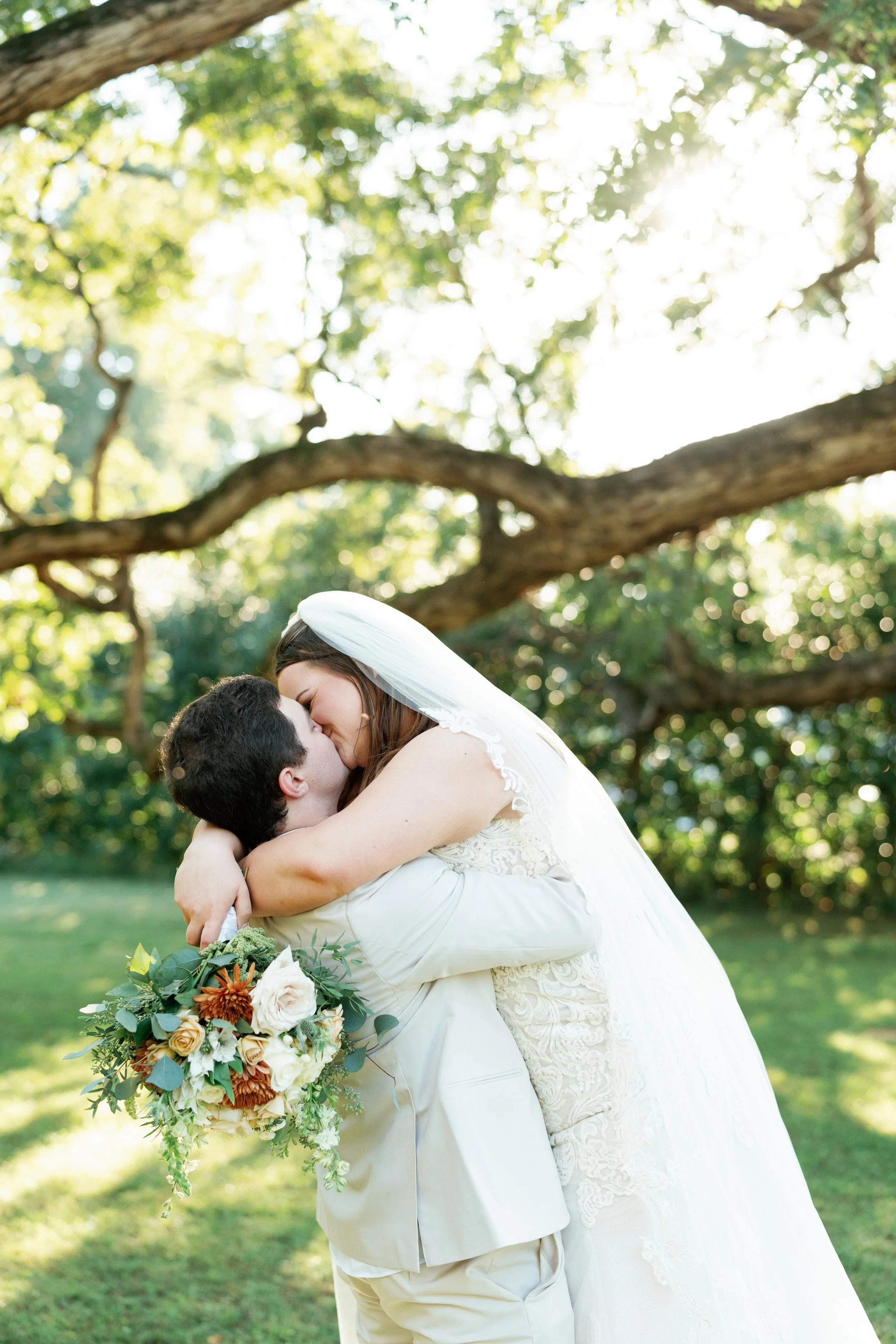 Bride and groom embracing under the historic twin oak trees at The Venue at Twin Oaks in Humboldt Tennessee photographed by West Tennessee wedding photographer Ashley Florence