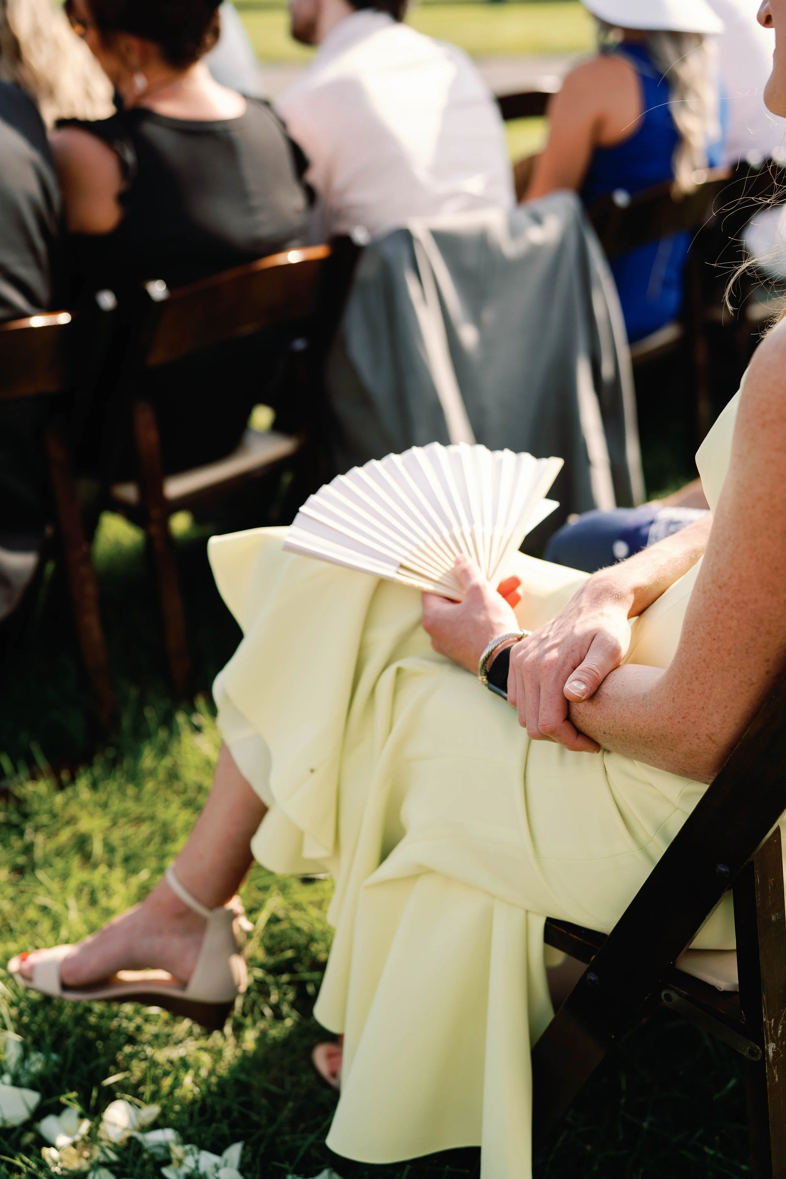 Candid wedding guest holding fan during outdoor summer ceremony, Tennessee wedding photograph