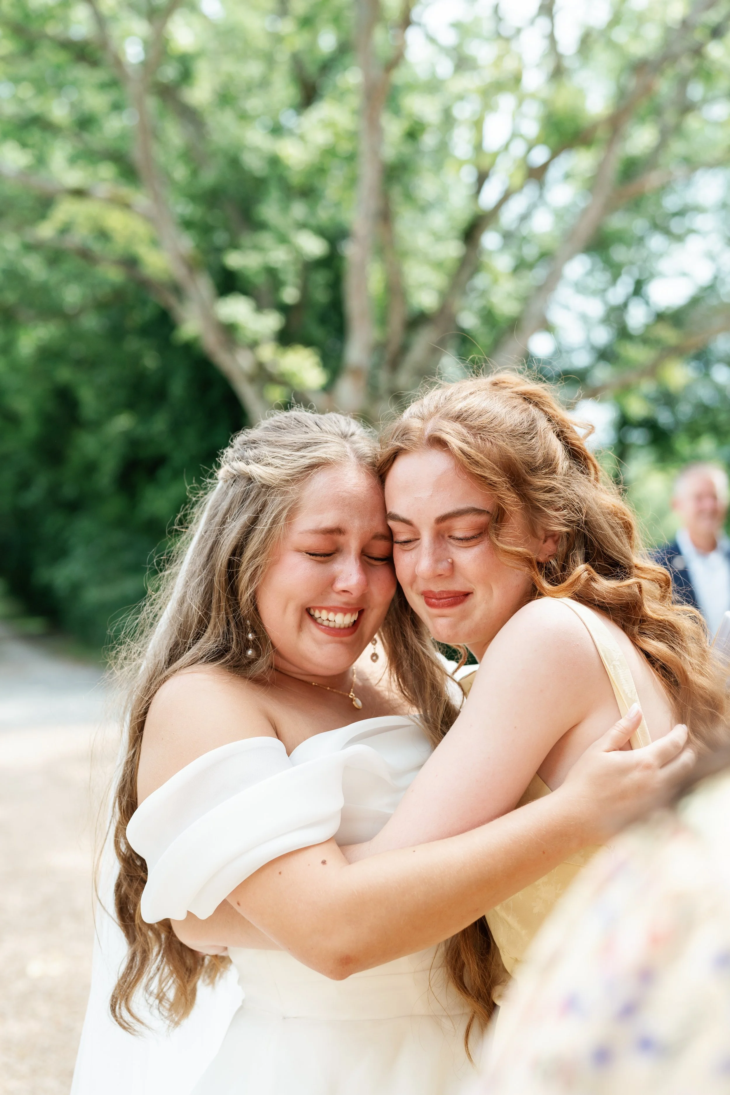 Bride sharing emotional hug with bridesmaid on wedding day, candid Tennessee wedding photography