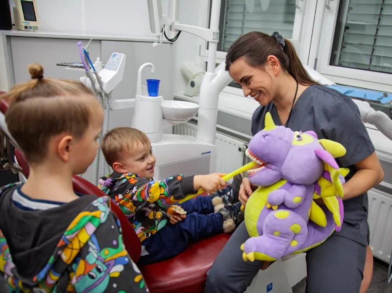dentist showing kinder how to brush teeth with dragon