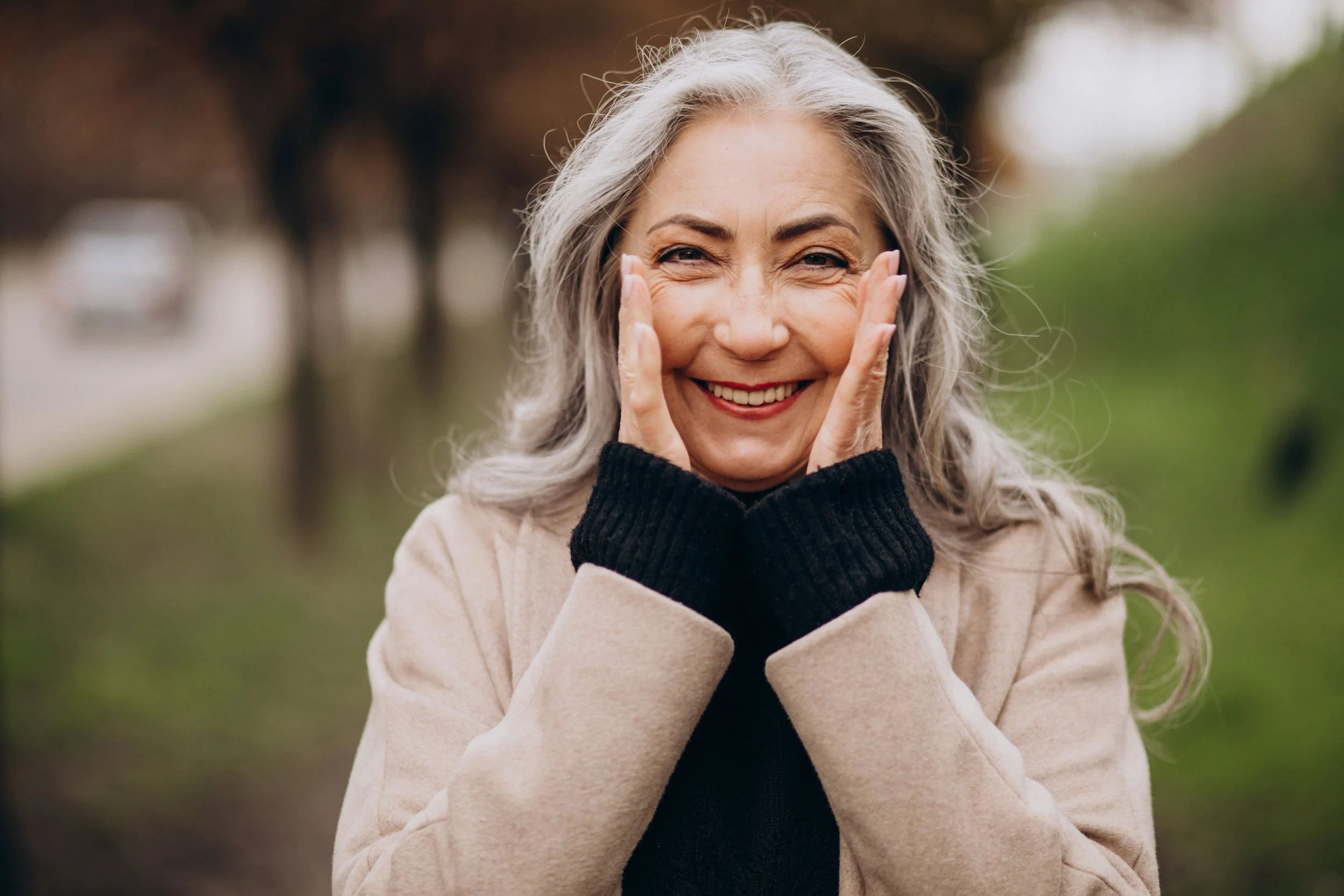 Older woman with long greying hair smiling happily with beautiful teeth
