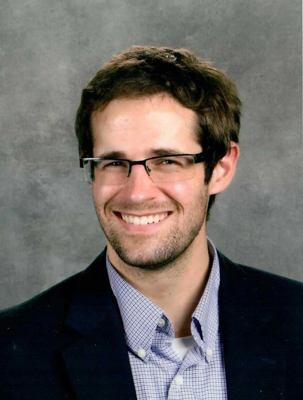 Ryan Benson, CFP, EA, tax expert in a suit and glasses smiling against a gray background.