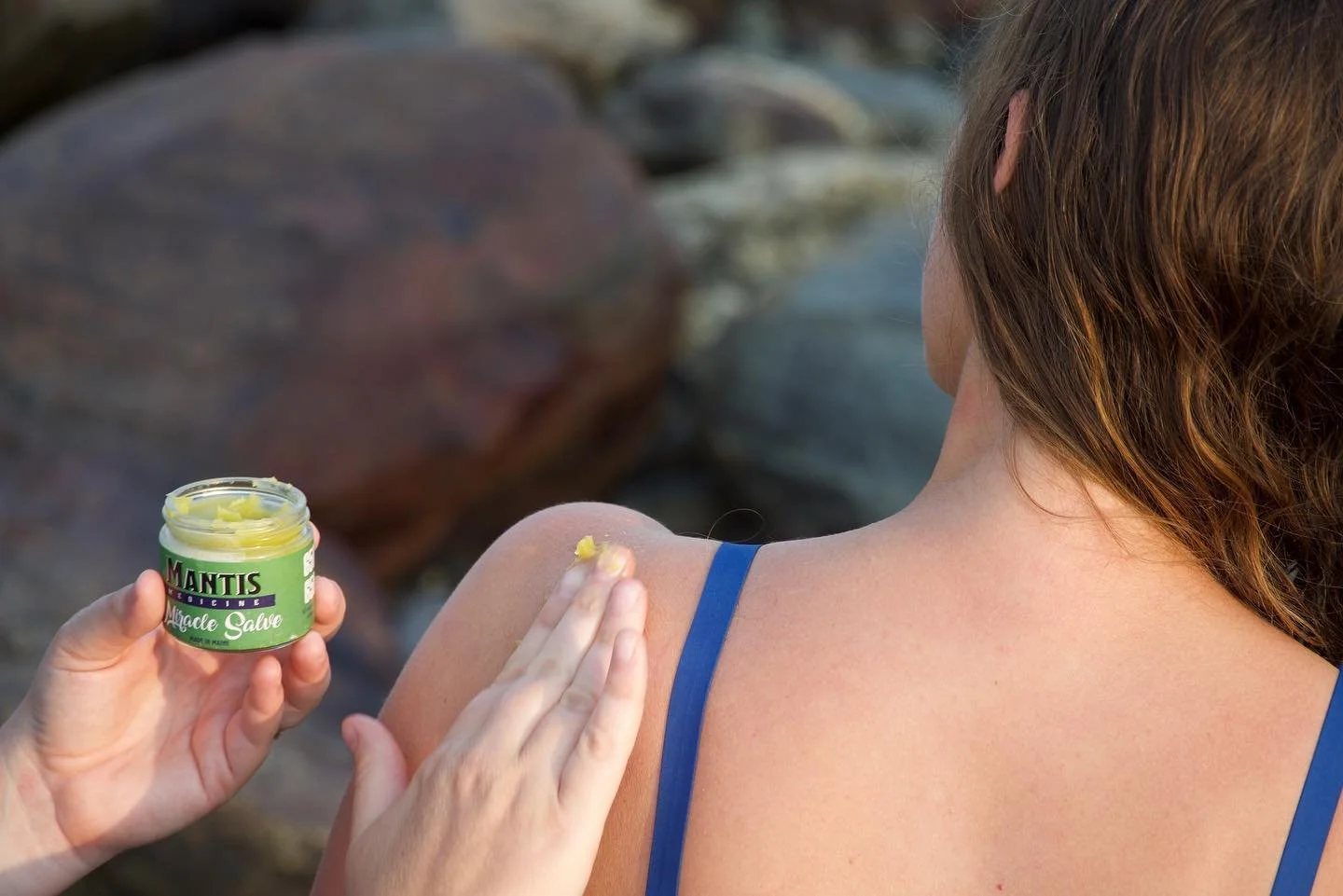 Person applying Mantis Medicine Miracle Salve to shoulder.