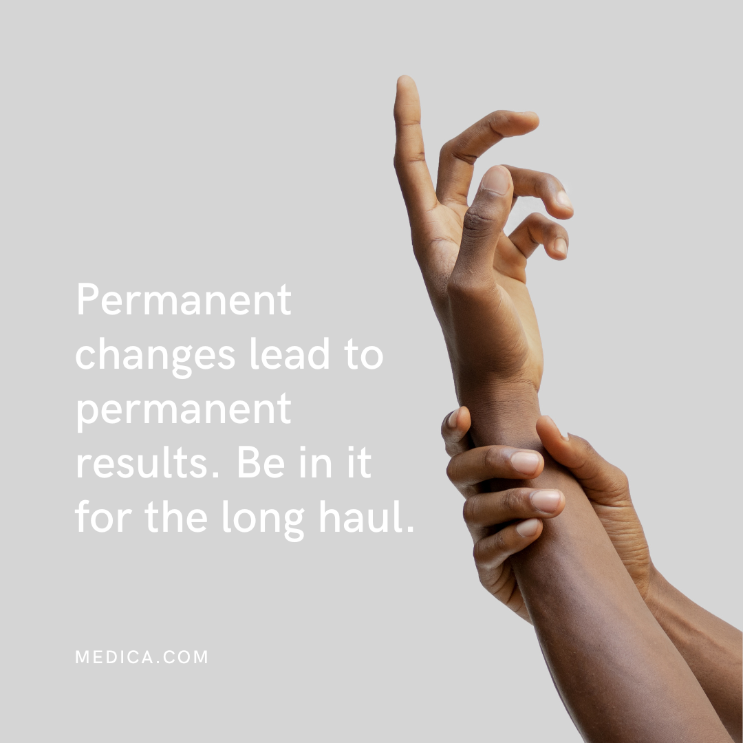 Close-up of two hands, one gripping the wrist of the other, against a gray background with white text that reads 'Permanent changes lead to permanent results. Be in it for the long haul. MEDICA.COM'.