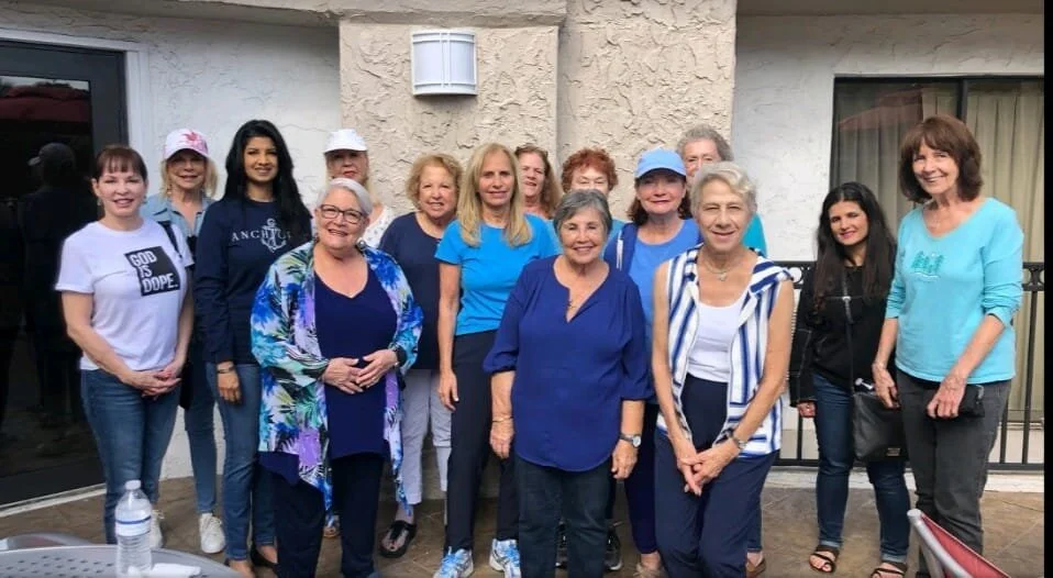 Group of women standing together outside a building, smiling at the camera.
