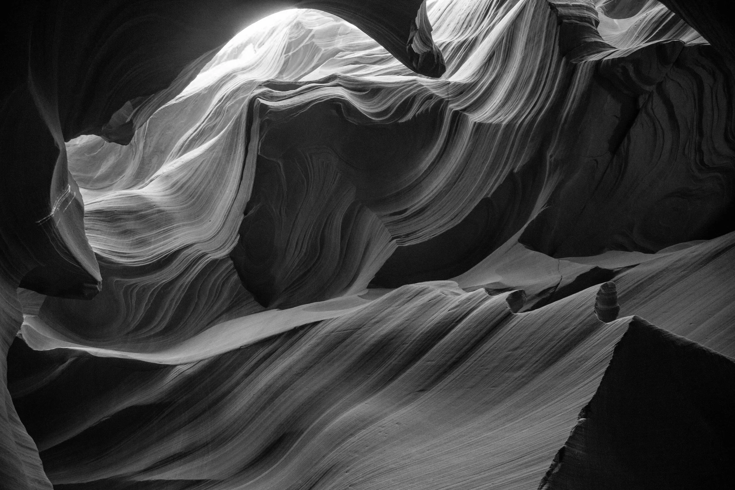 Smooth, layered sandstone walls inside a narrow slot canyon with warm orange and brown tones and light filtering from above.