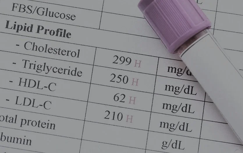 A medical report showing lipid profile results with high cholesterol, triglyceride, HDL-C, LDL-C, and total protein levels, with a blood test vial placed on top.
