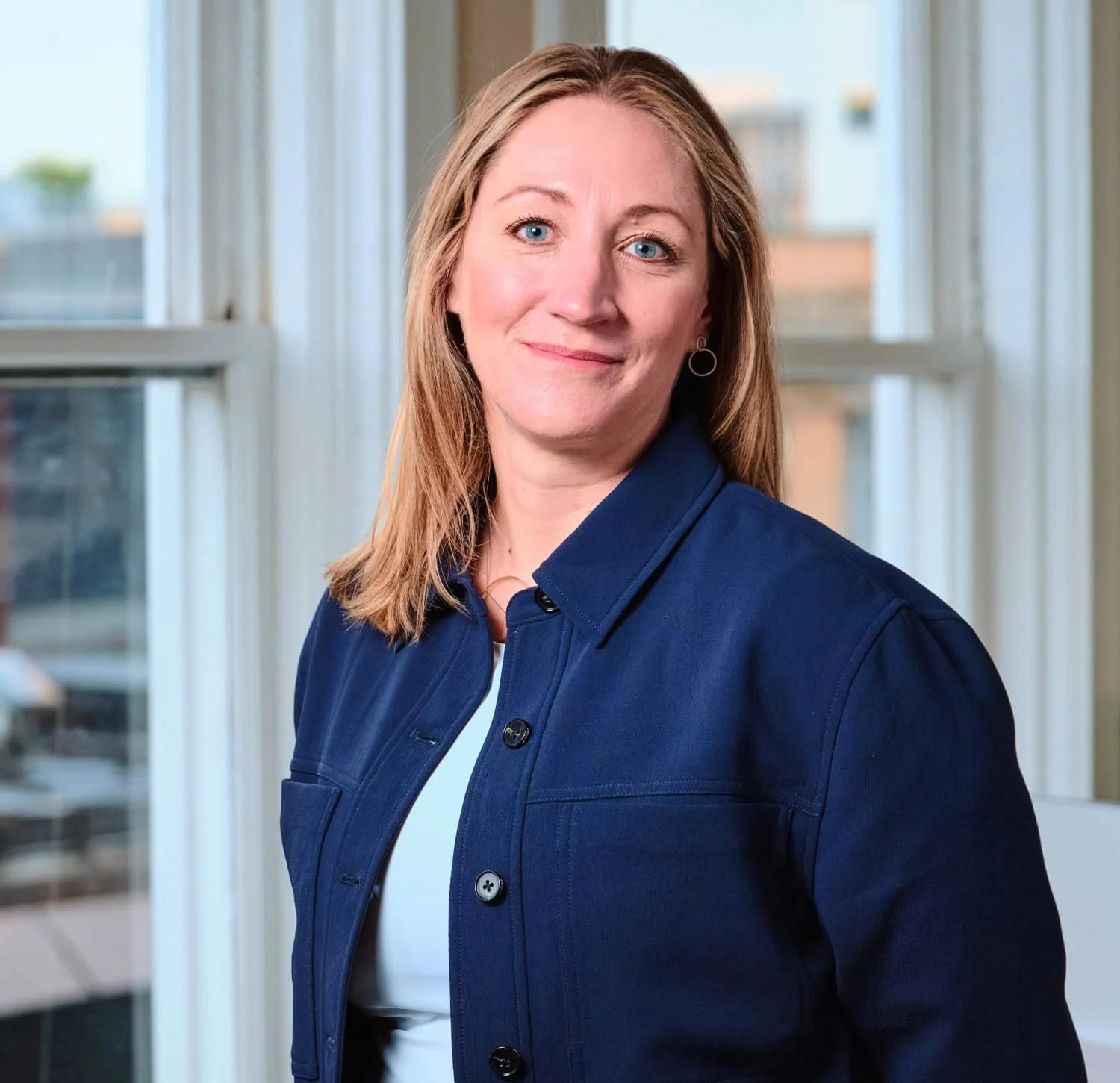 Martina Soderlund. Founding Principal + Building Performance Engineer P.Eng. at reLoad Sustainable Design Inc. A woman with shoulder-length light brown hair, blue eyes, wearing a navy blue jacket and white top.