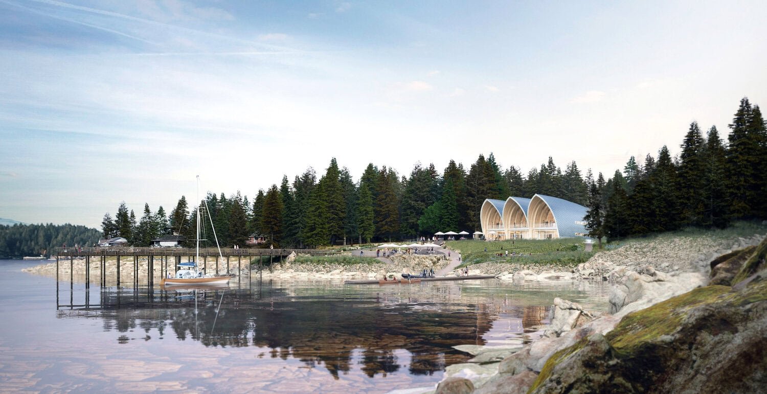 View of a lakeside with a marina, sailboats, and a grassy area with people. In the background, there is the Pender Harbour Ocean Discovery Station a zero carbon building.