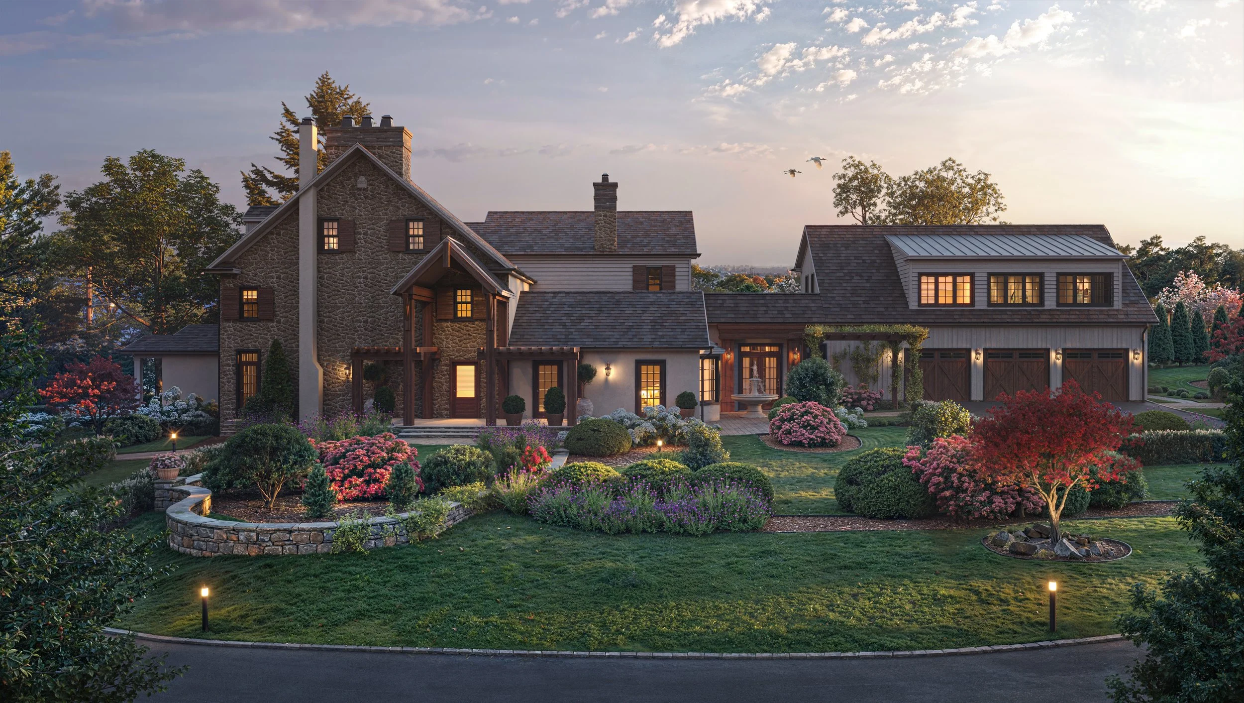 A large house with a stone and wood exterior, surrounded by a landscaped garden with flowering bushes, trees, and a curved stone wall, during sunset.