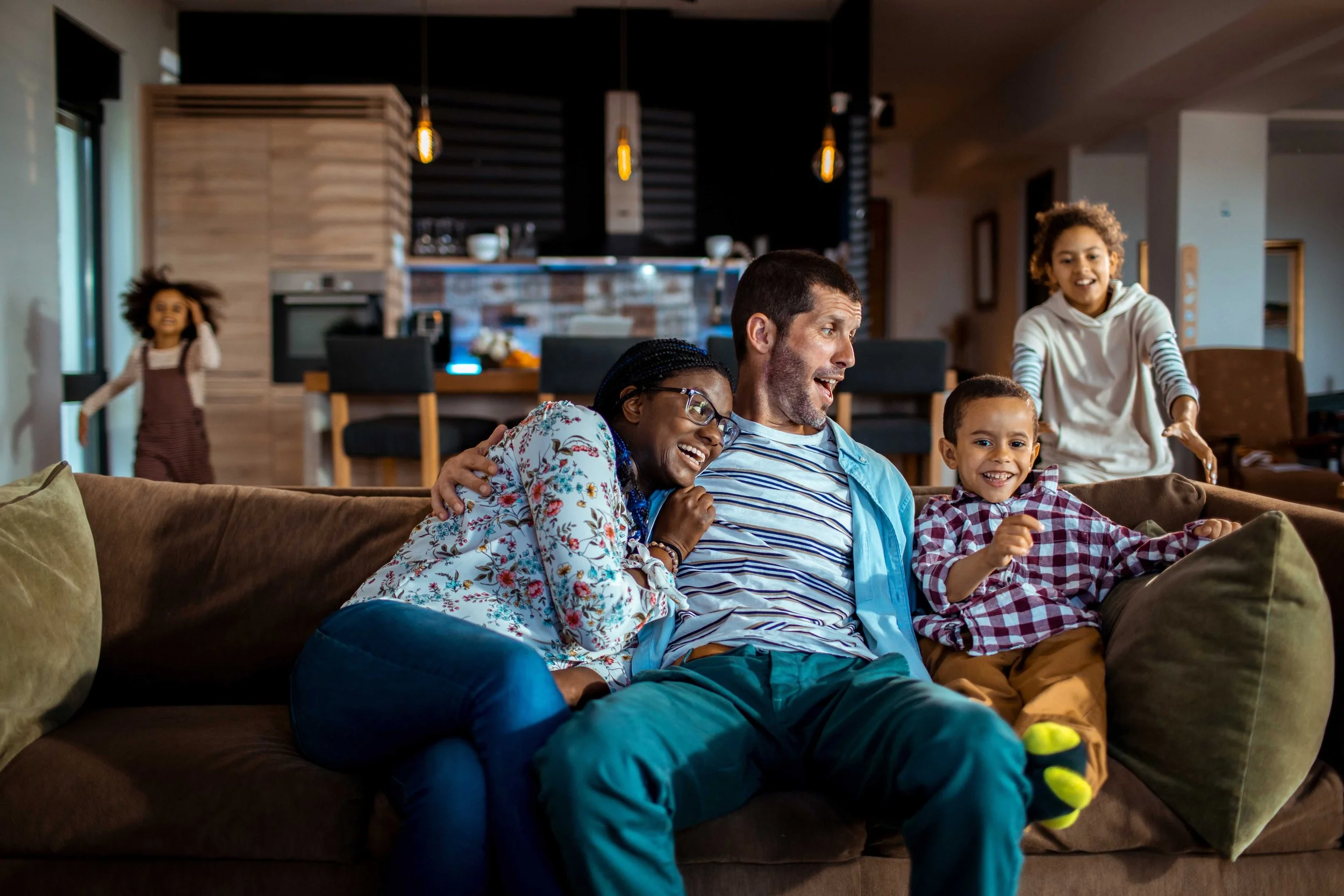 Mixed couple spending time with their kids in the living room