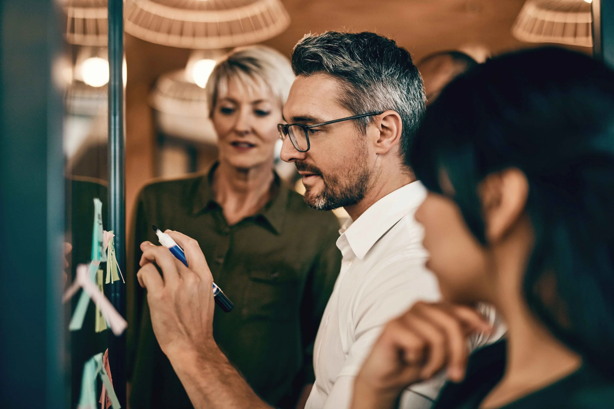 Man brainstorming with female co-workers using post-it notes