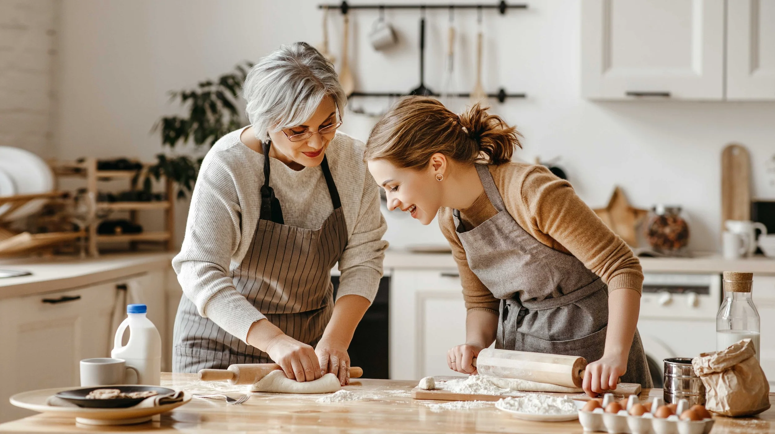 Senior woman kneading dough with daughter in the kitchen