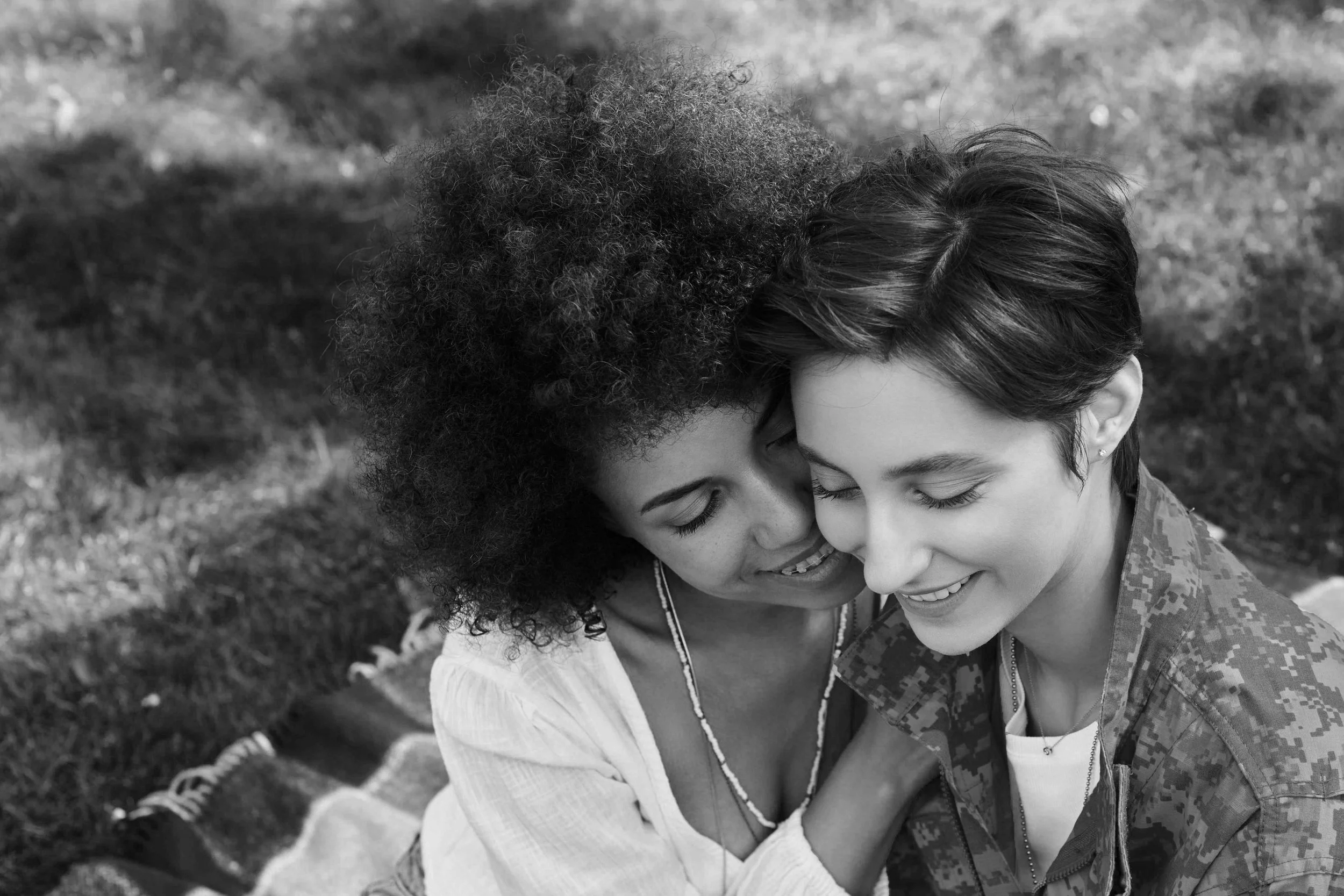 A joyful reunion as a soldier receives a warm welcome from her wife in a beautiful outdoor setting.
