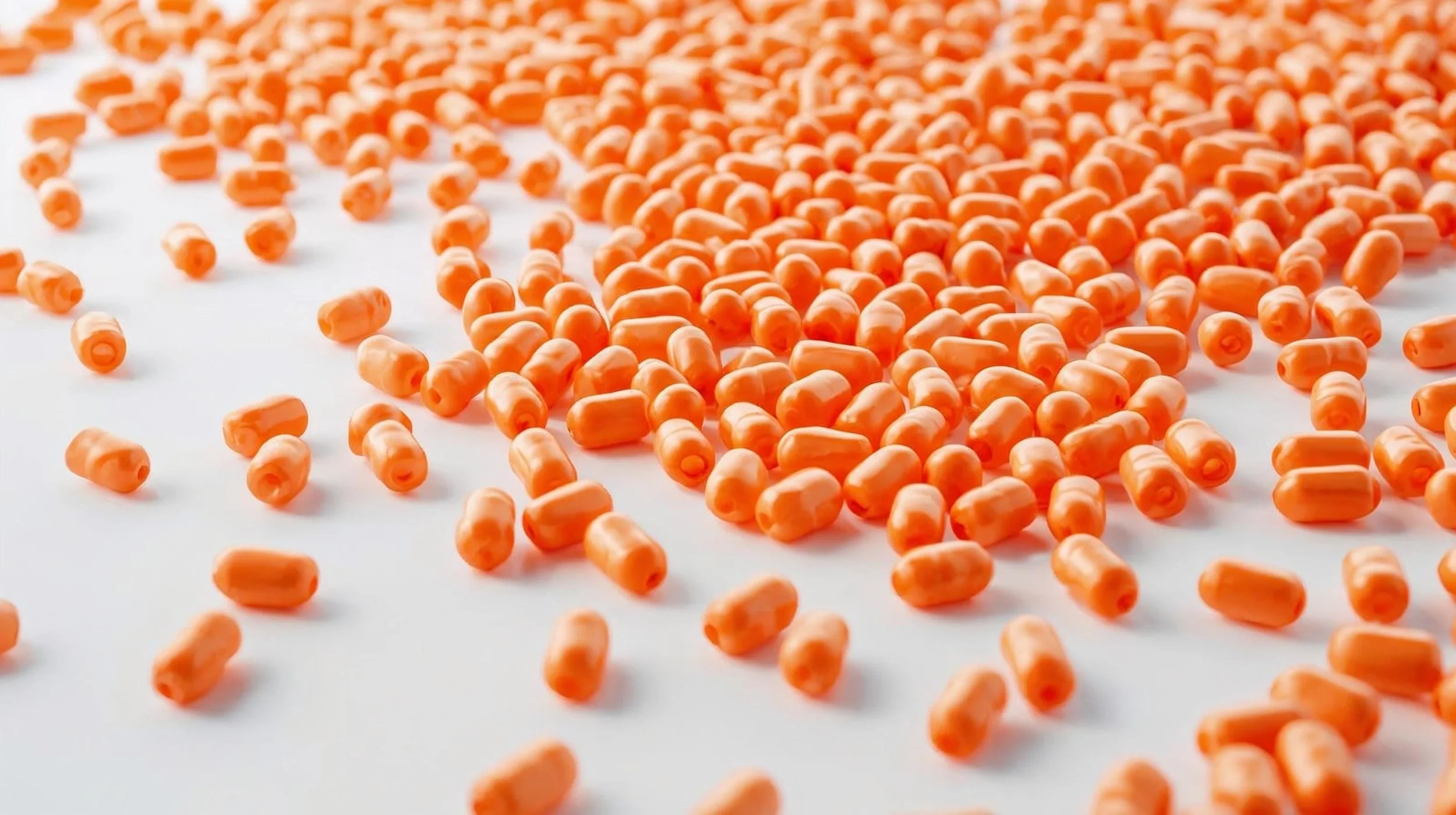 Multiple small orange PVC end caps scattered on a white surface.