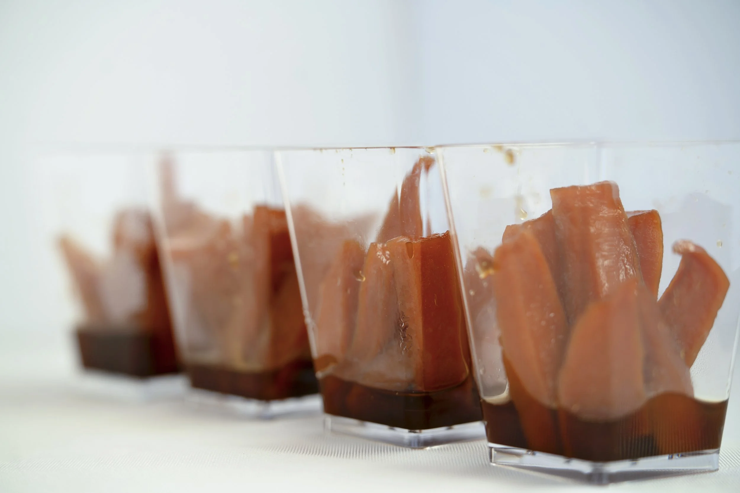 Three clear glass containers filled with orange carrot sticks, with some liquid at the bottom.