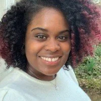 Close-up of a woman with curly hair smiling outdoors