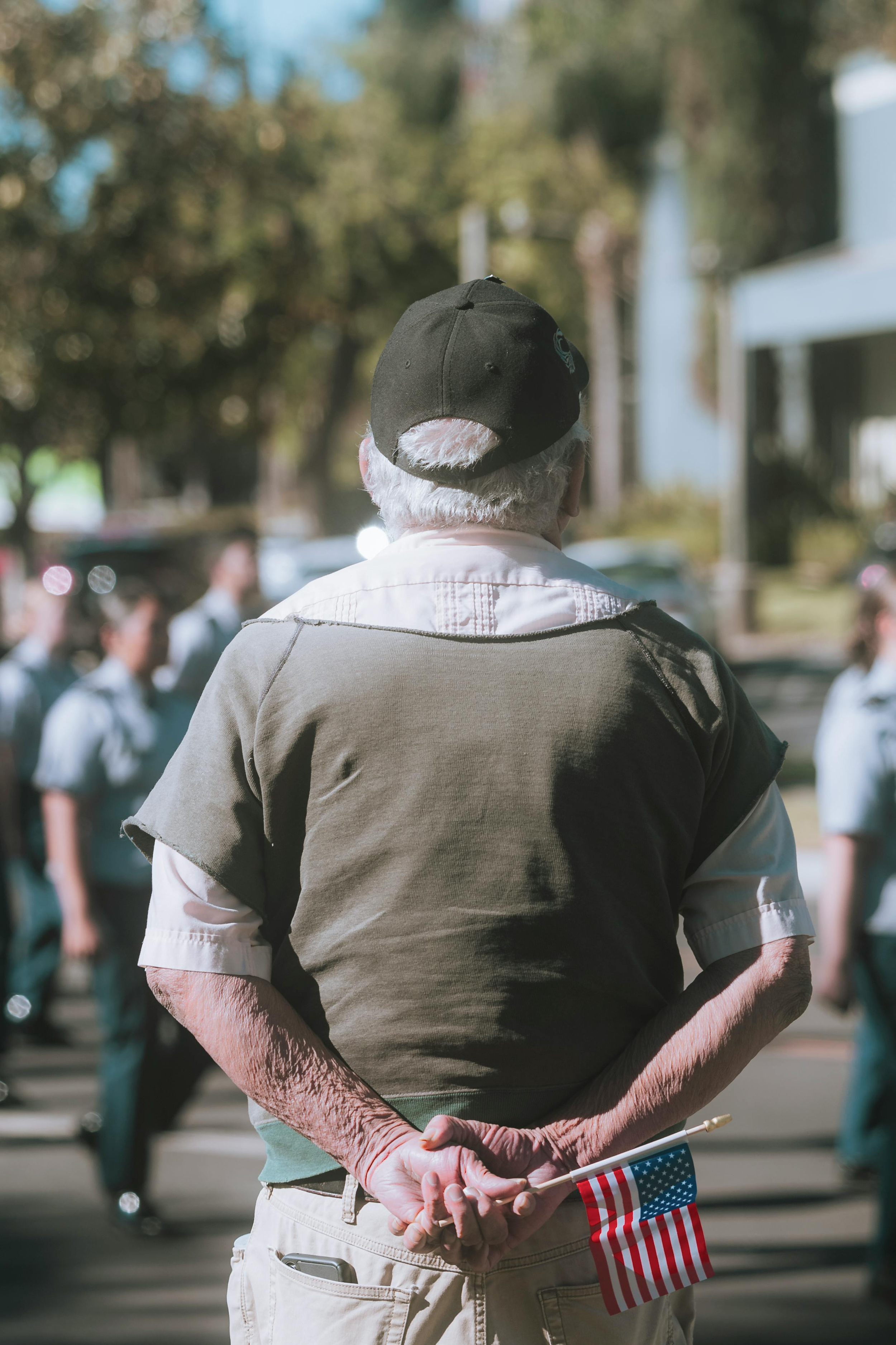 A veteran standing with a small American flag held behind his back, symbolizing the silent strength and long-term stewardship required in first responder non-profit leadership.