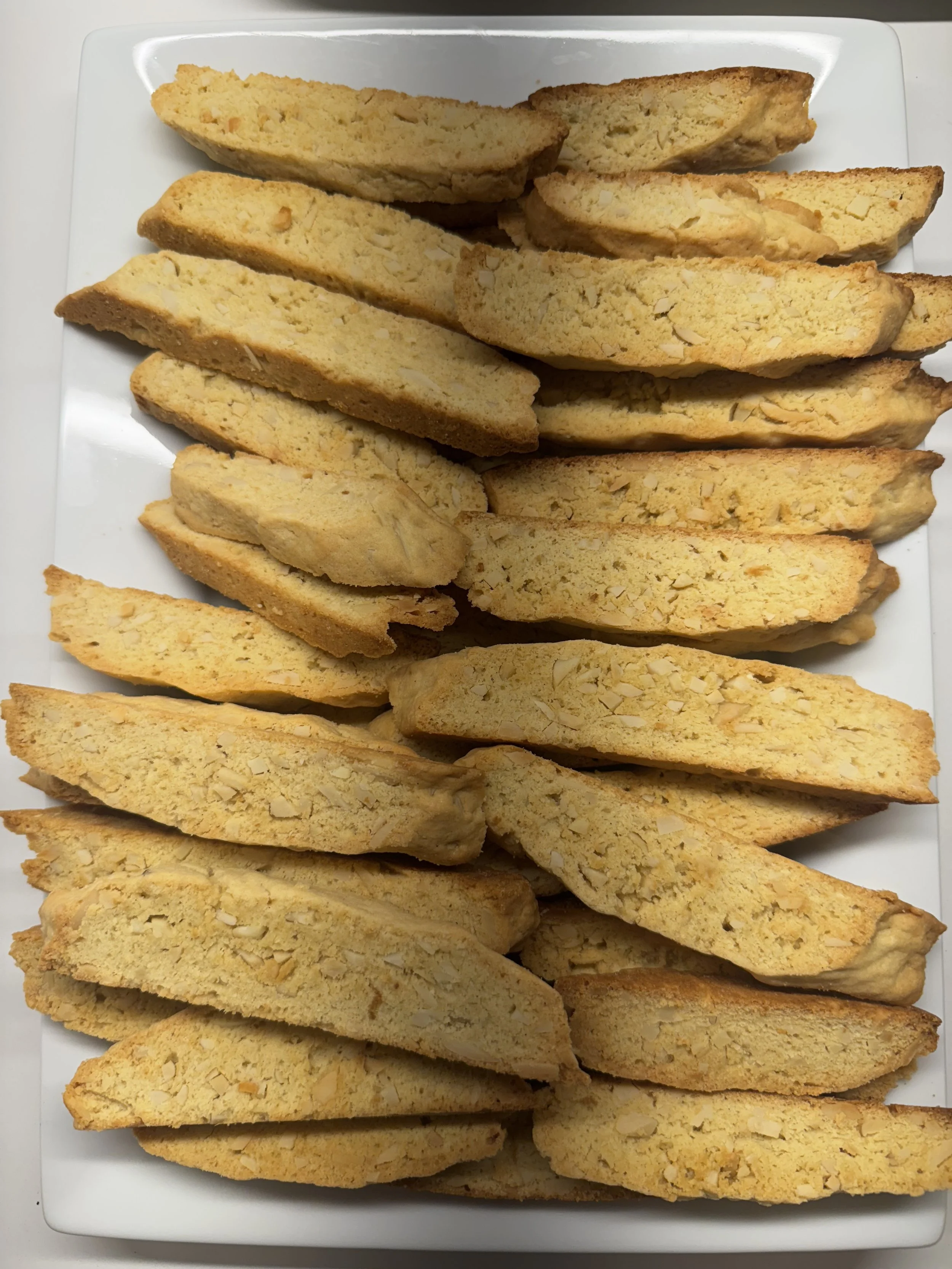 Multiple almond flour biscotti cookies arranged on a white rectangular plate.
