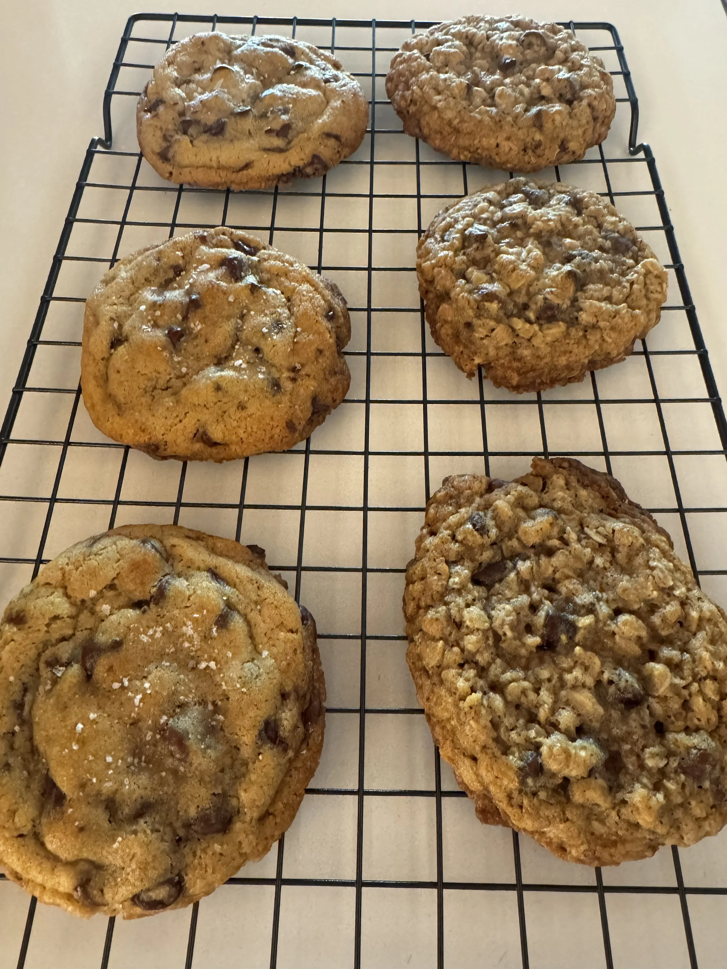 Six large chocolate chip cookies cooling on a wire rack.