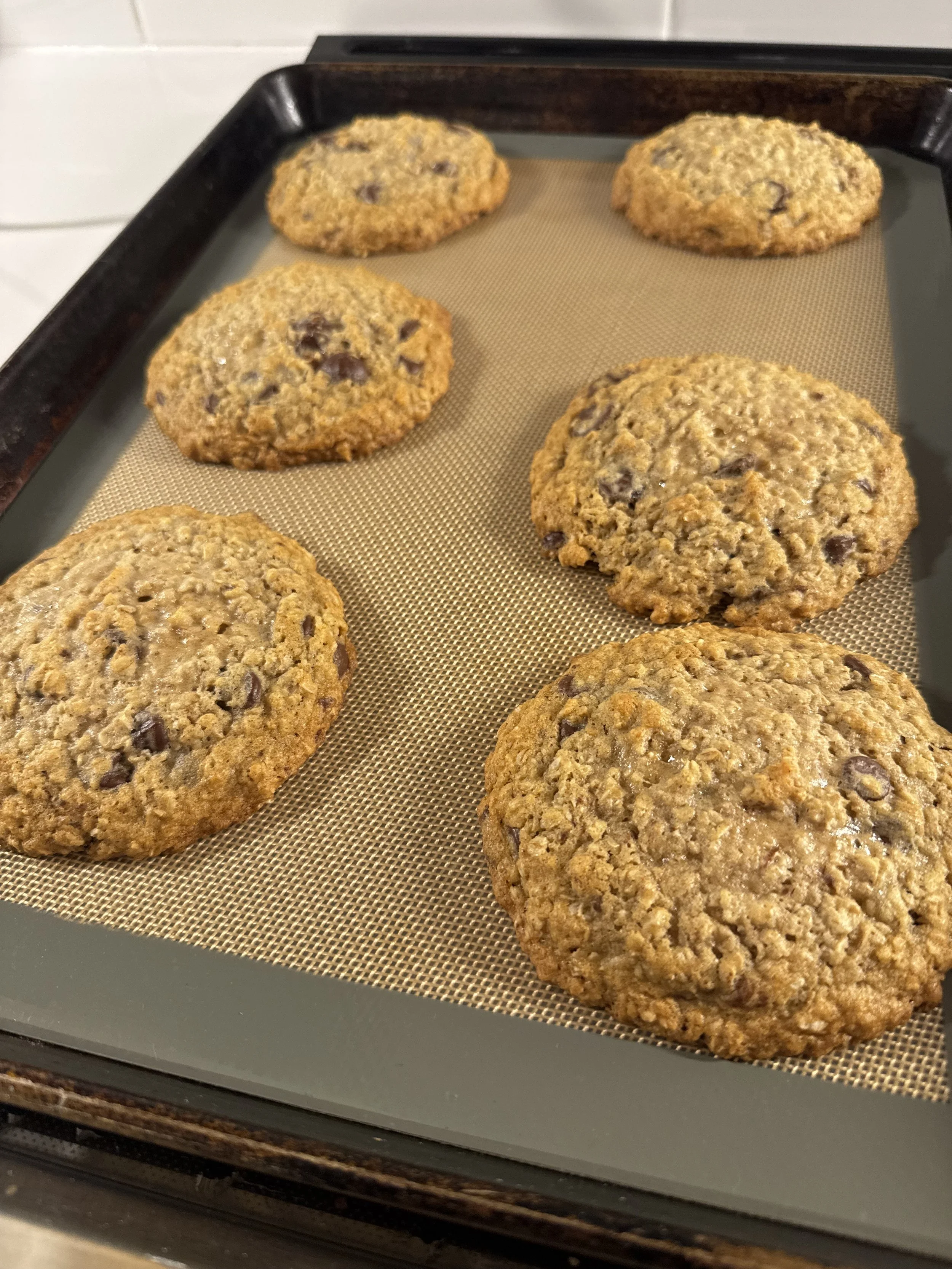 Freshly baked chocolate chip cookies on a baking sheet.