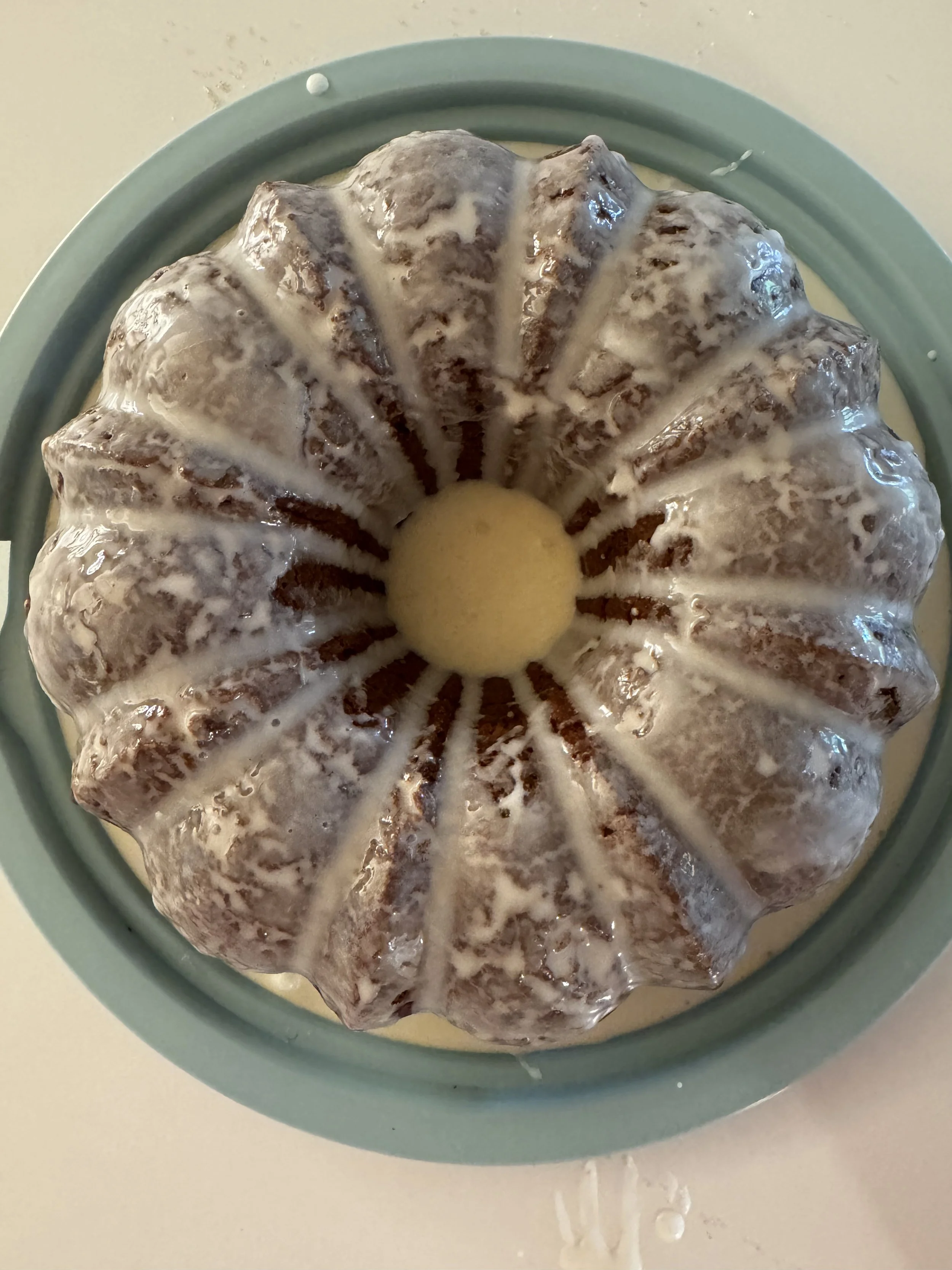 Bundt cake with white glaze on a blue cake stand.