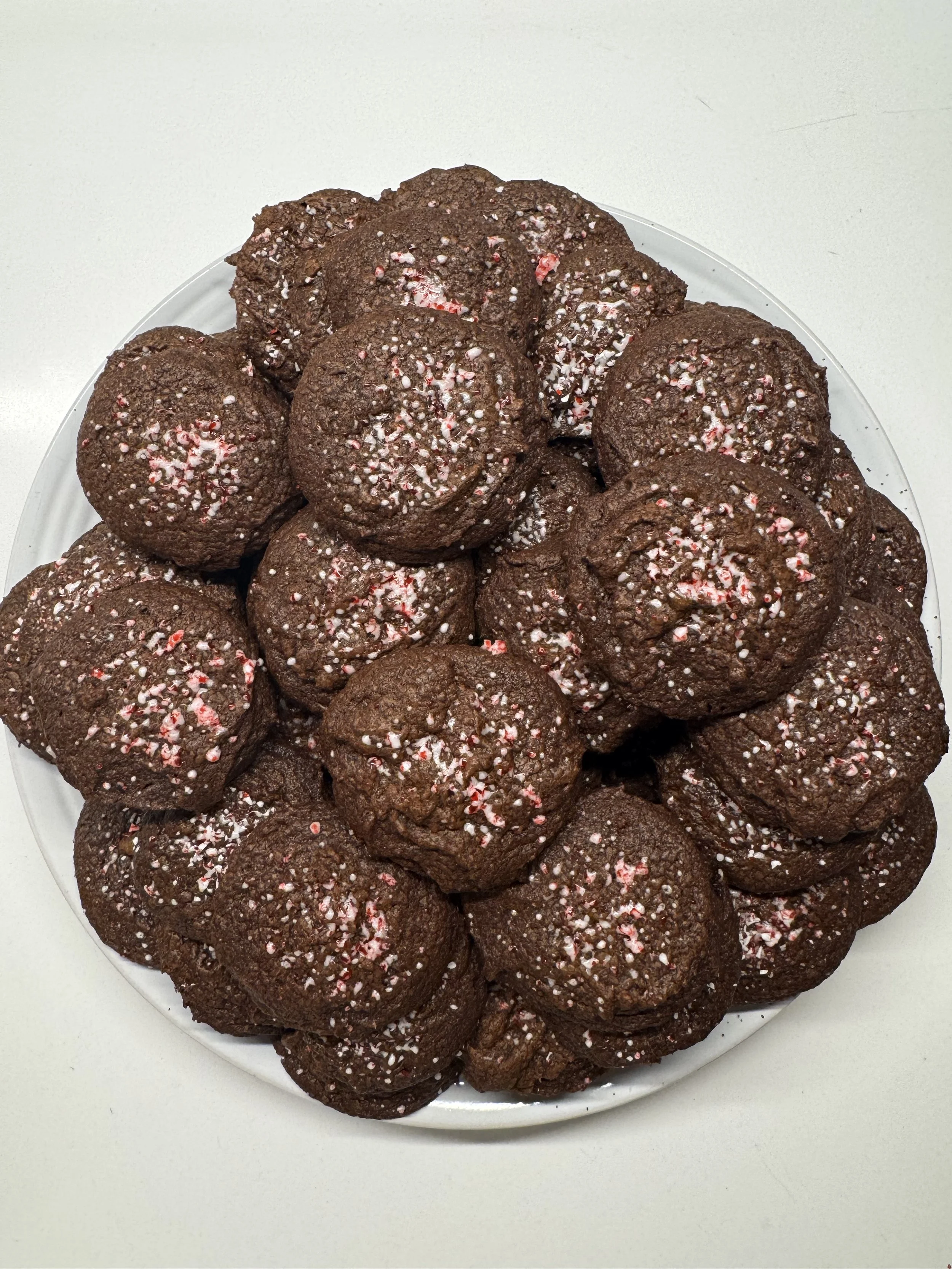 Plate of chocolate cookies topped with crushed peppermint candies.