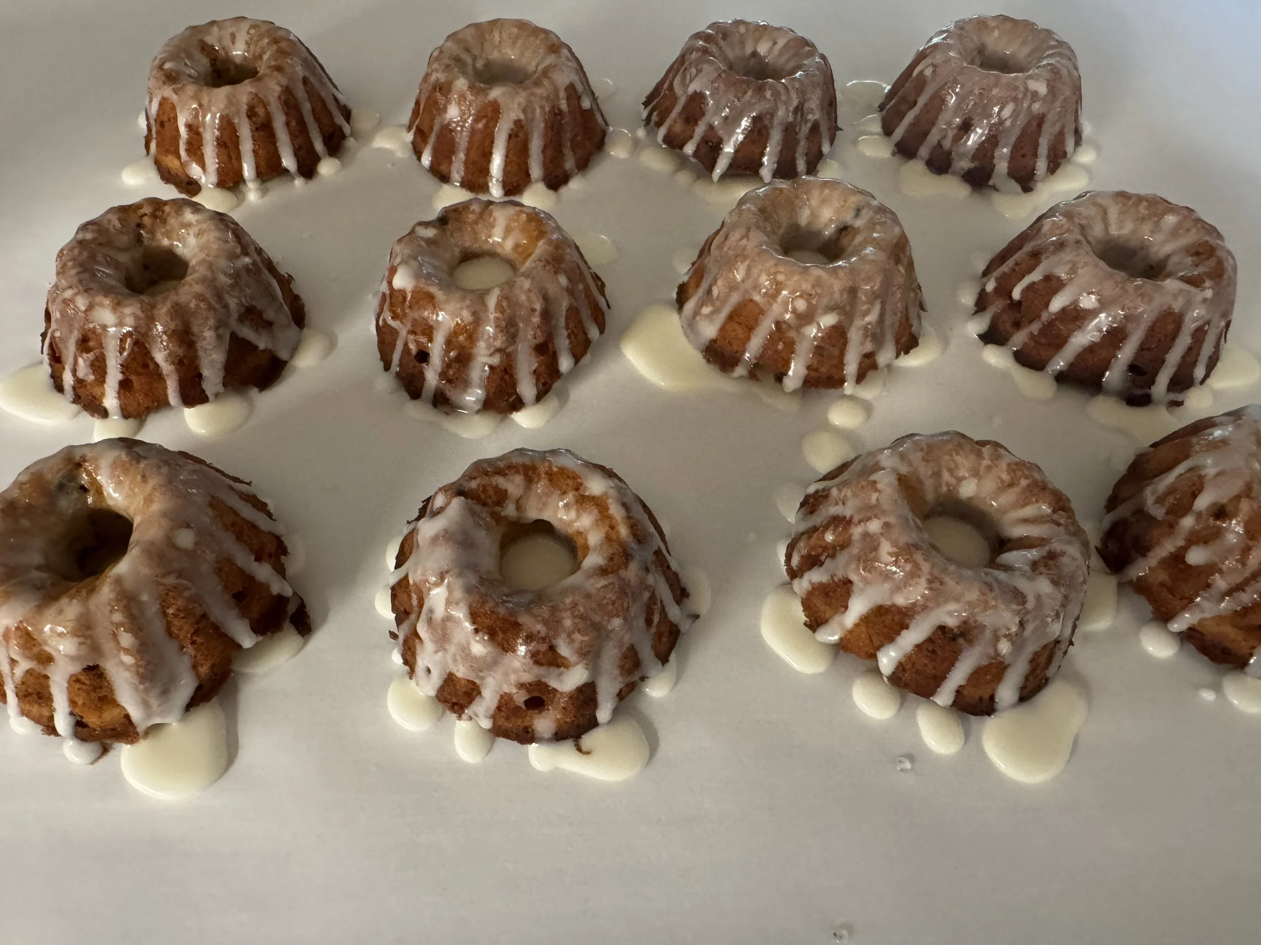 A tray of small bundt cakes with glaze drizzled on top.