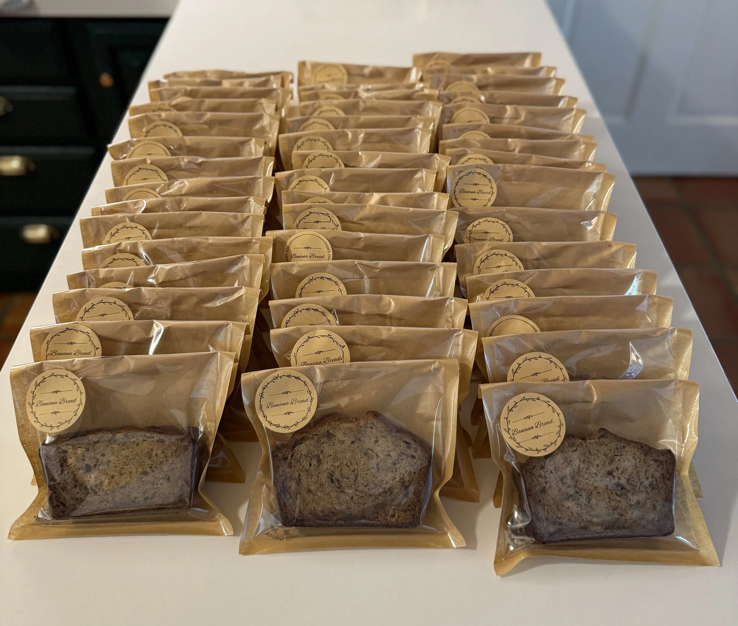 Multiple individually wrapped slices of banana bread on a white surface.